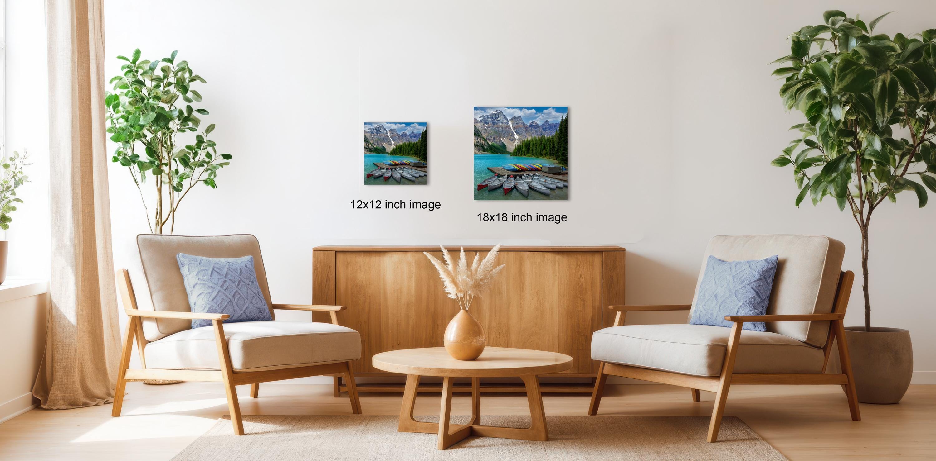 a living room with two chairs, a coffee table, and two framed landscape photographs hanging on the wall.