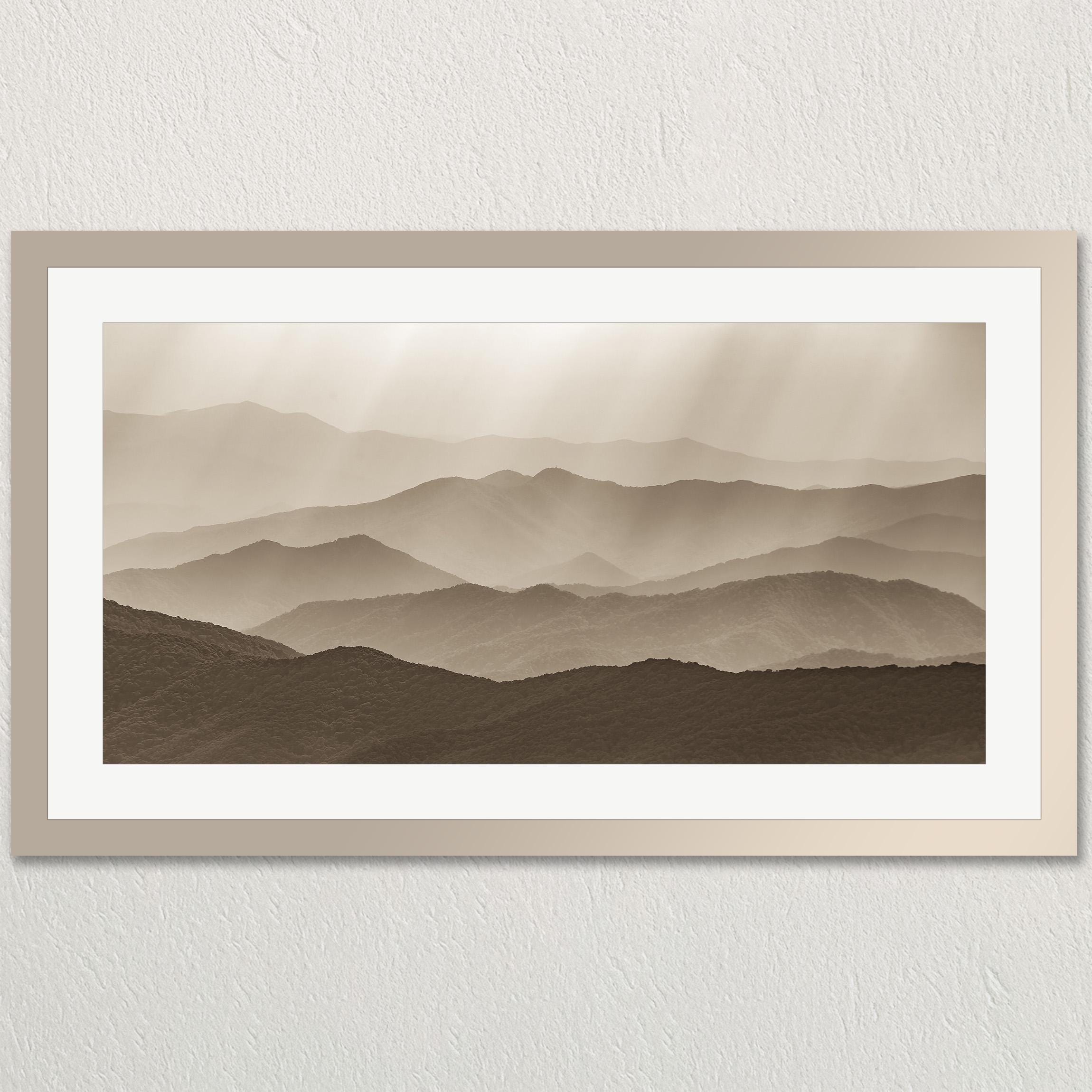 A framed photograph depicting a serene landscape of rolling hills and mountains, with a hazy, atmospheric quality to the scene.