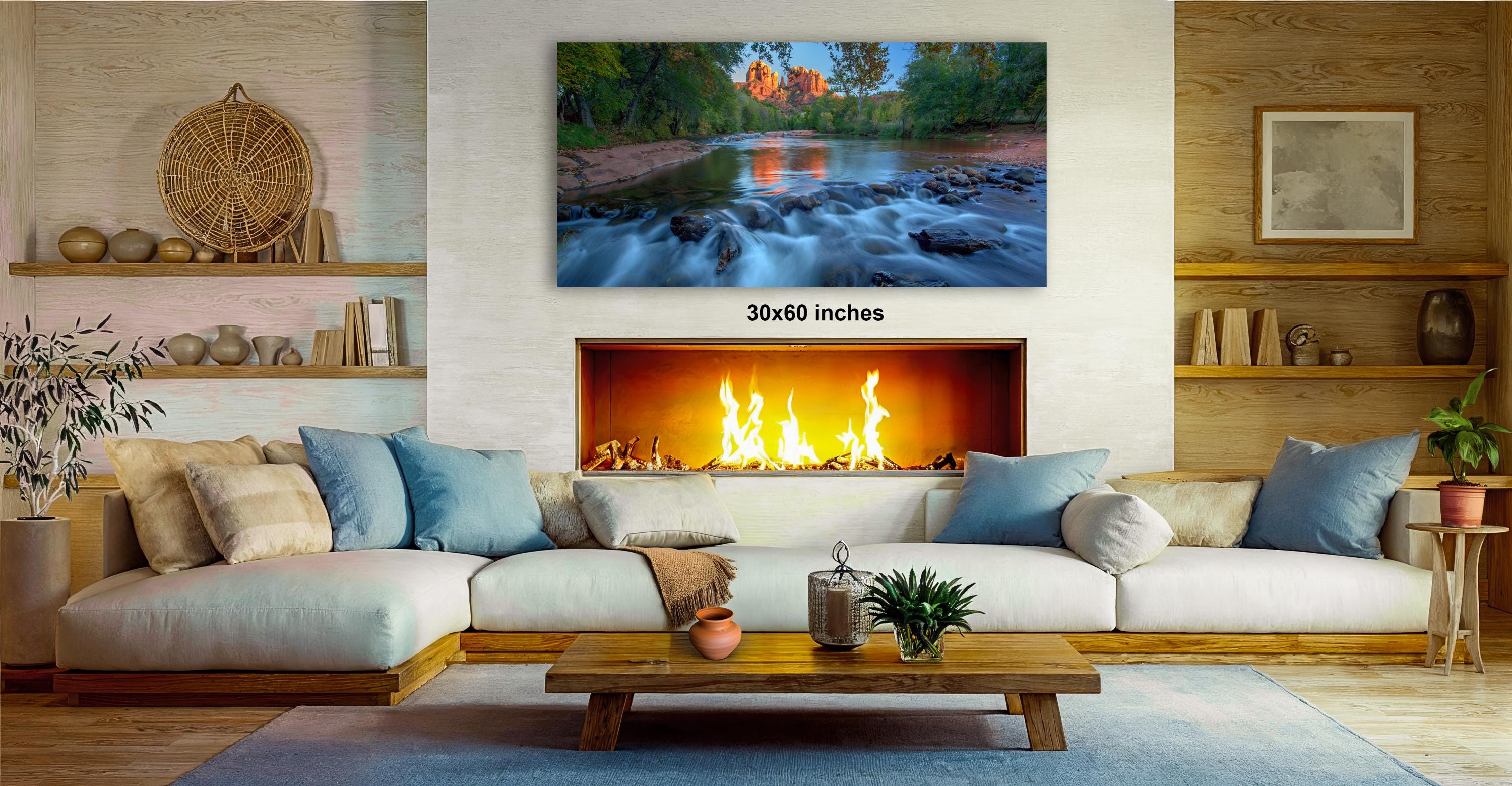 a cozy living room with a fireplace, a large painting of a river, and a wooden coffee table.