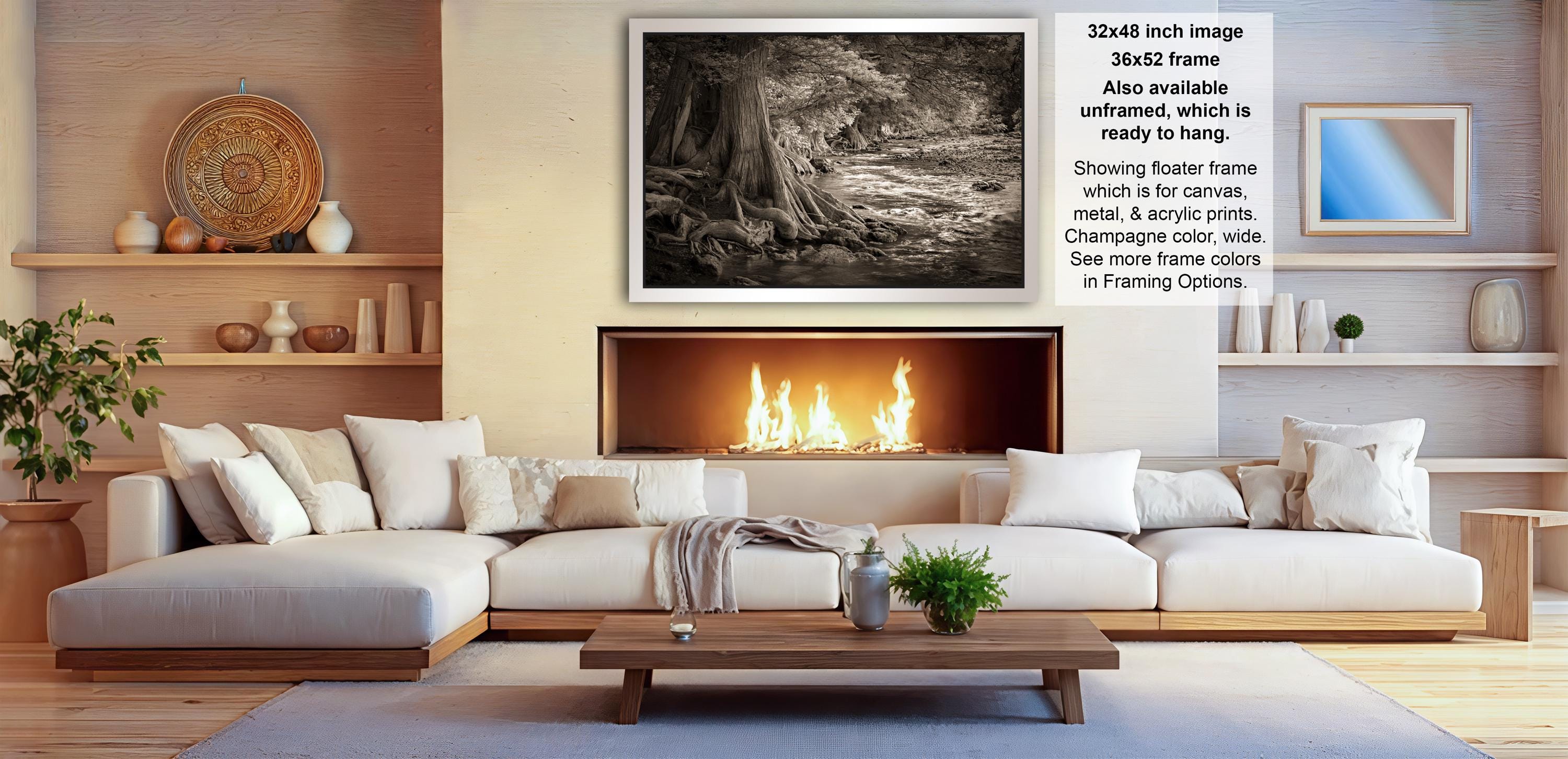 The image is a modern living room with a large white sectional sofa, a fireplace, and a wooden coffee table. The room has a warm and inviting atmosphere, with various decorative elements such as vases, potted plants, and a mirror. The focal point of the room is the fireplace, which has a fire burning, creating a cozy ambiance. The image also includes text that provides information about the frame size and material, as well as a description of the frame's design.