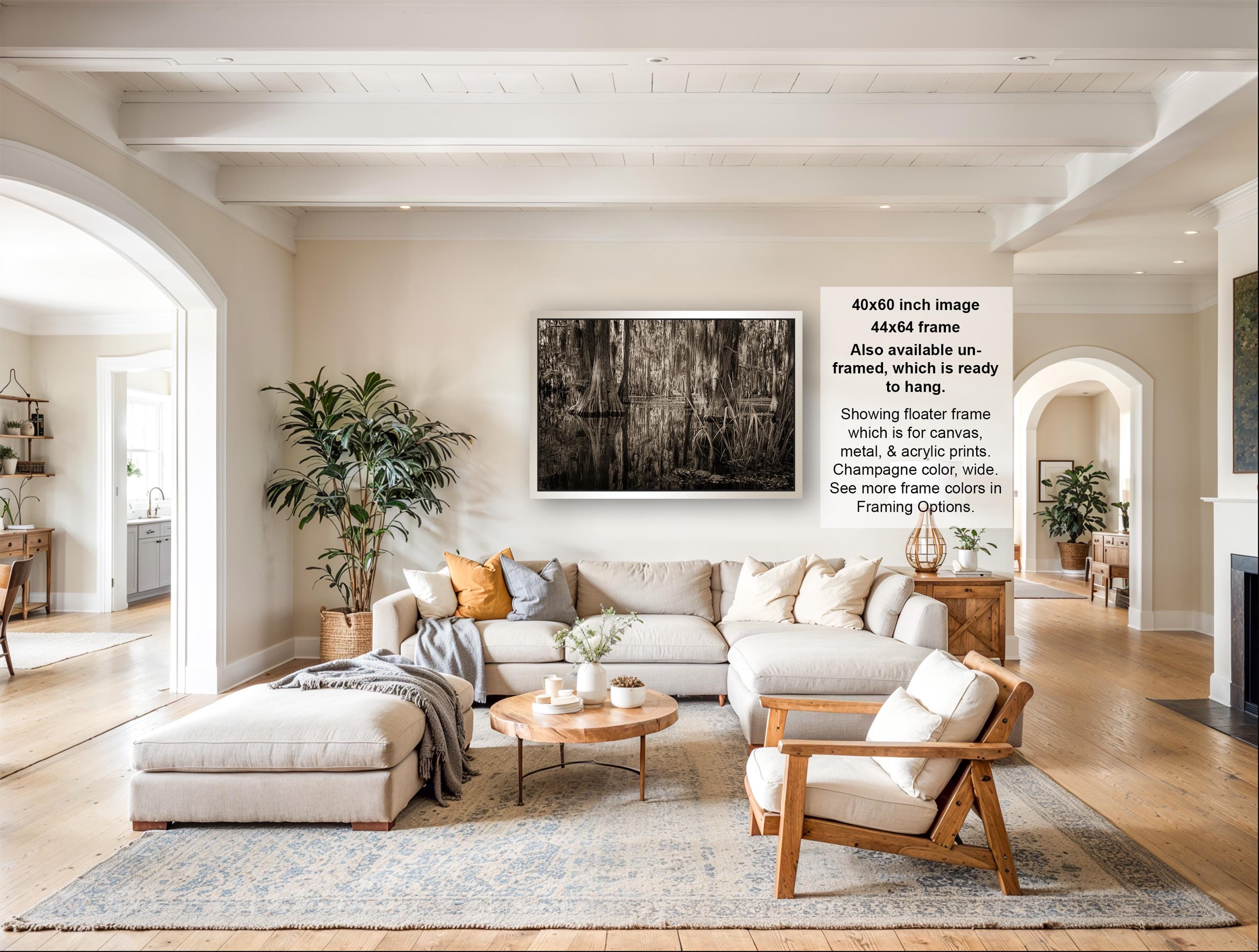 The image is a spacious living room with a large sectional sofa, a coffee table, and a fireplace. The room is decorated with various plants and has a neutral color palette.
