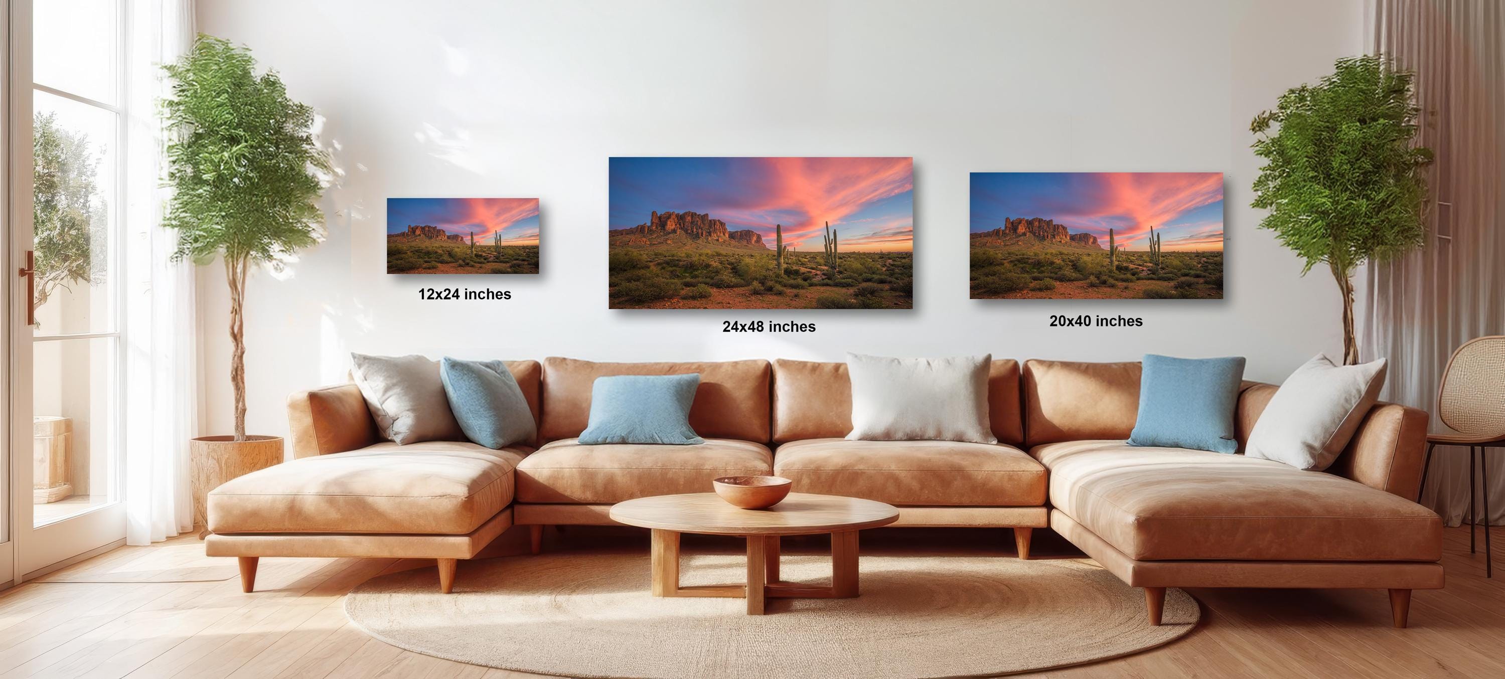 a living room with a large sectional sofa, a coffee table, and three framed landscape paintings hanging on the wall above the sofa.