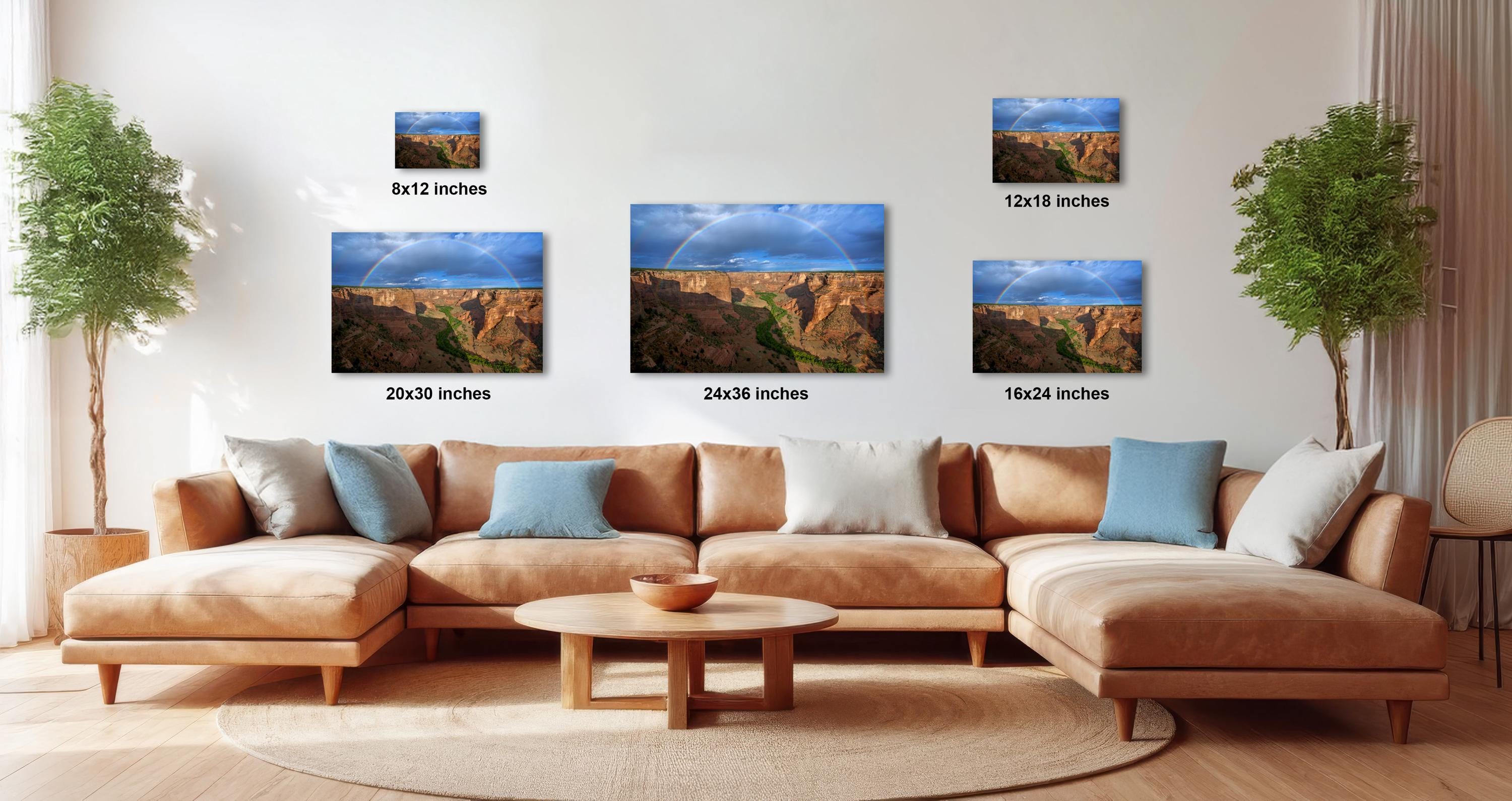 a large, brown sectional sofa with multiple pillows, a wooden coffee table, and a potted plant in the background. The sofa is positioned in front of a wall with three framed landscape photographs of the Grand Canyon, each with a different size and resolution.