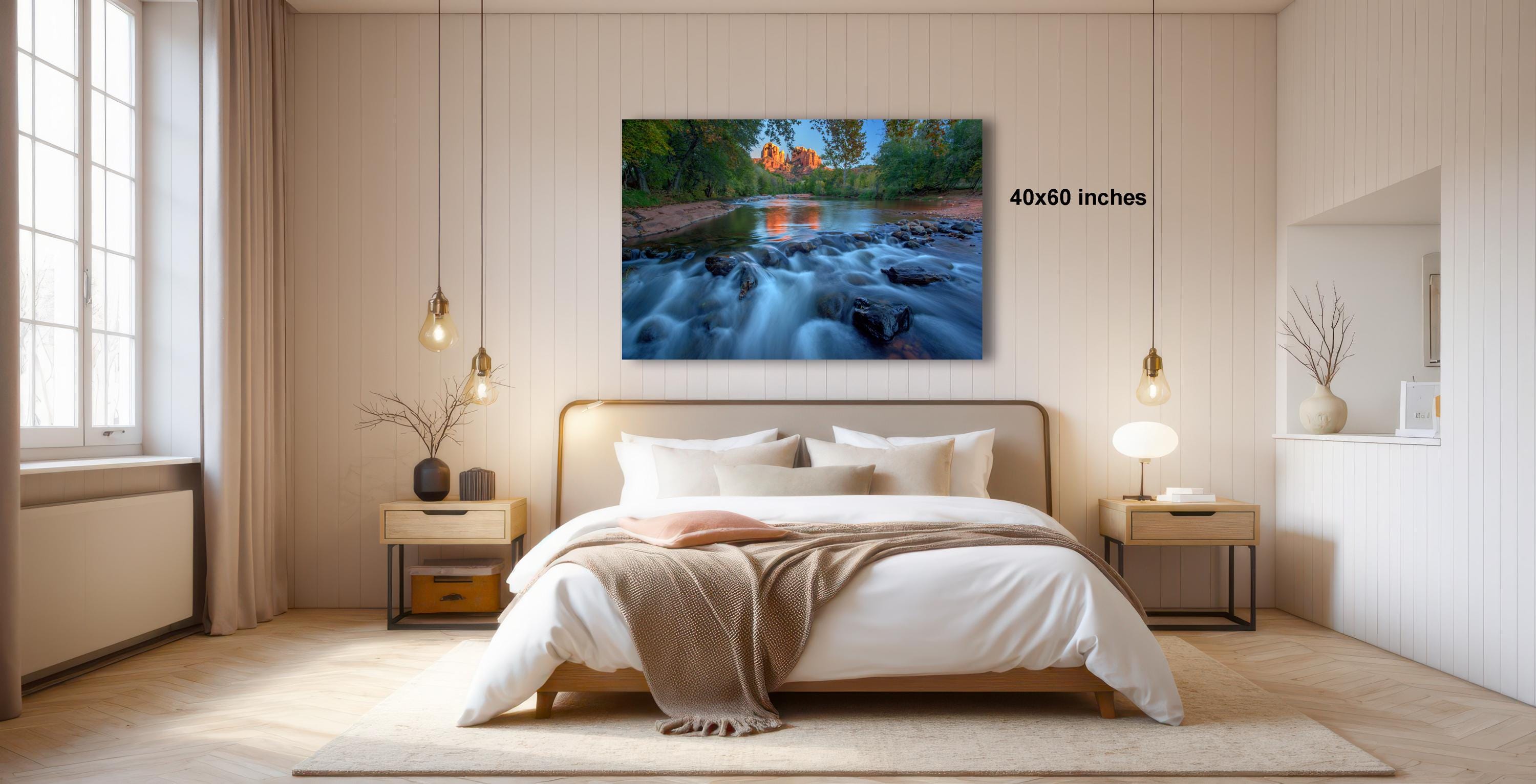 a serene bedroom with a large bed, wooden furniture, and a painting of a river flowing through a forest.