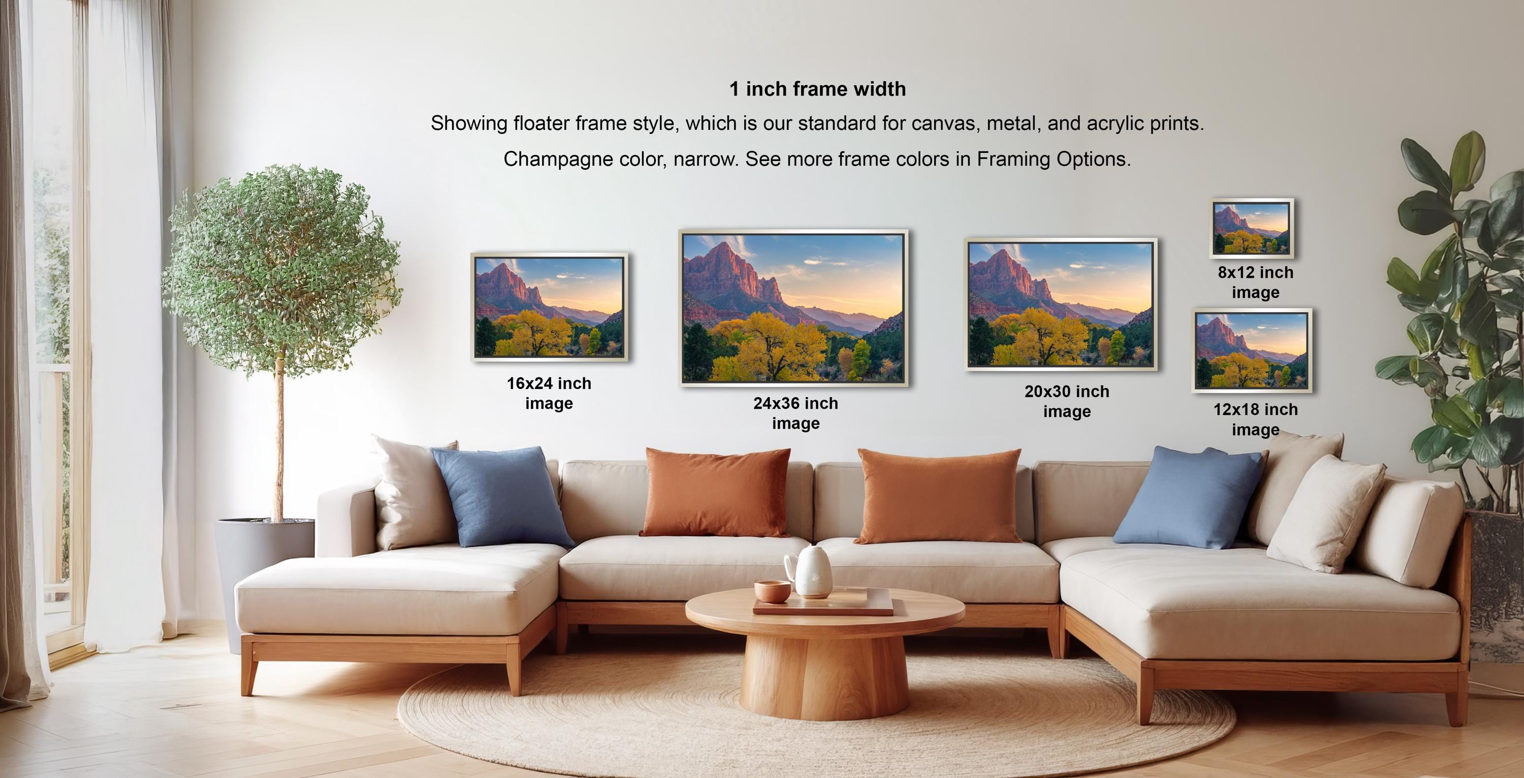a living room with a large sectional sofa and a coffee table. There are four framed landscape paintings displayed on the wall, each with a different frame size ranging from 16" to 20" inches. The paintings depict various scenic landscapes, including mountains, forests, and bodies of water. The arrangement of the paintings and the overall layout of the living room create a cozy and inviting atmosphere.