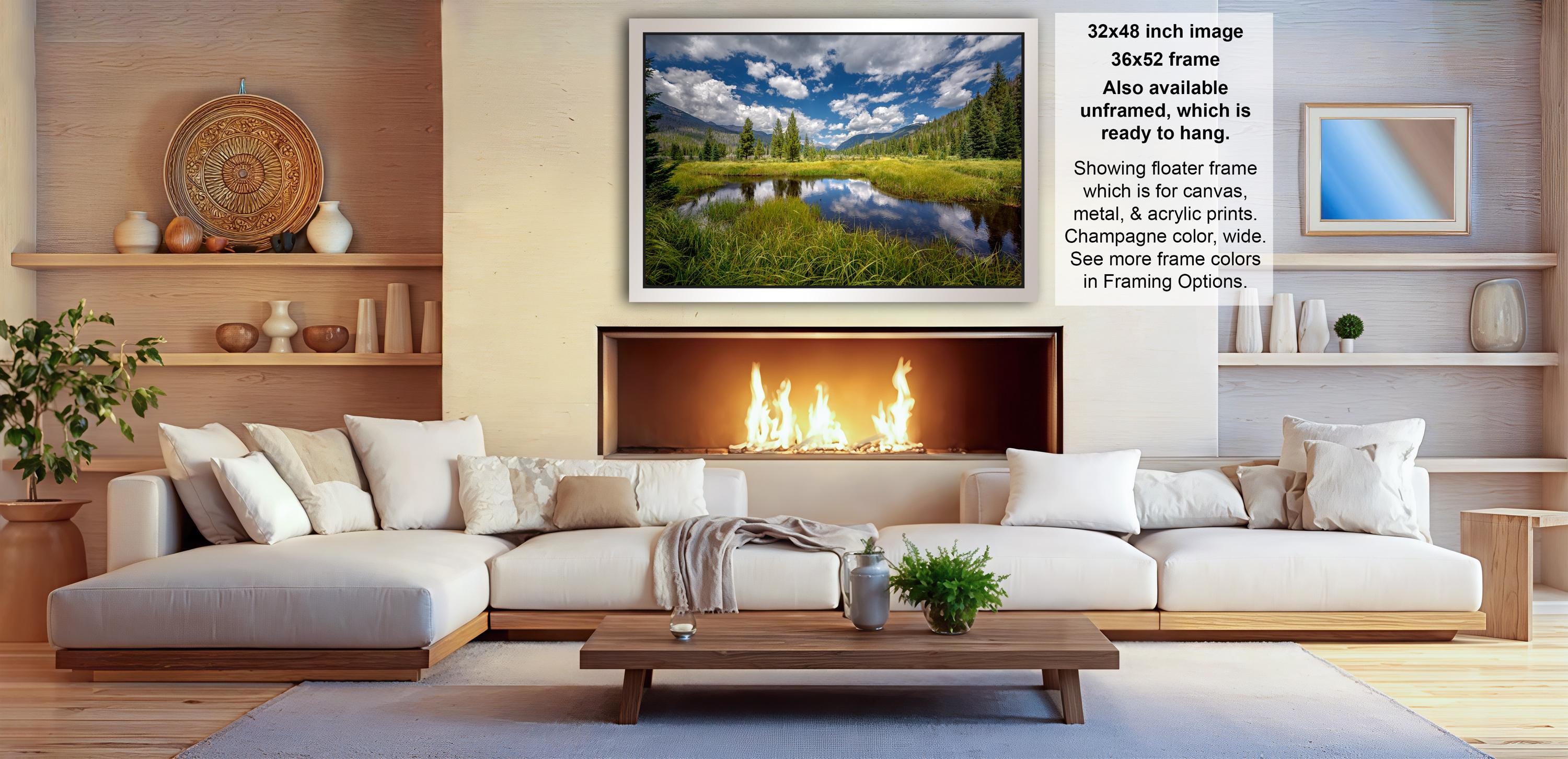 a cozy living room with a fireplace, white sofas, and a coffee table. The room has a warm and inviting atmosphere, with a fireplace providing a focal point and a painting of a serene landscape hanging above it.