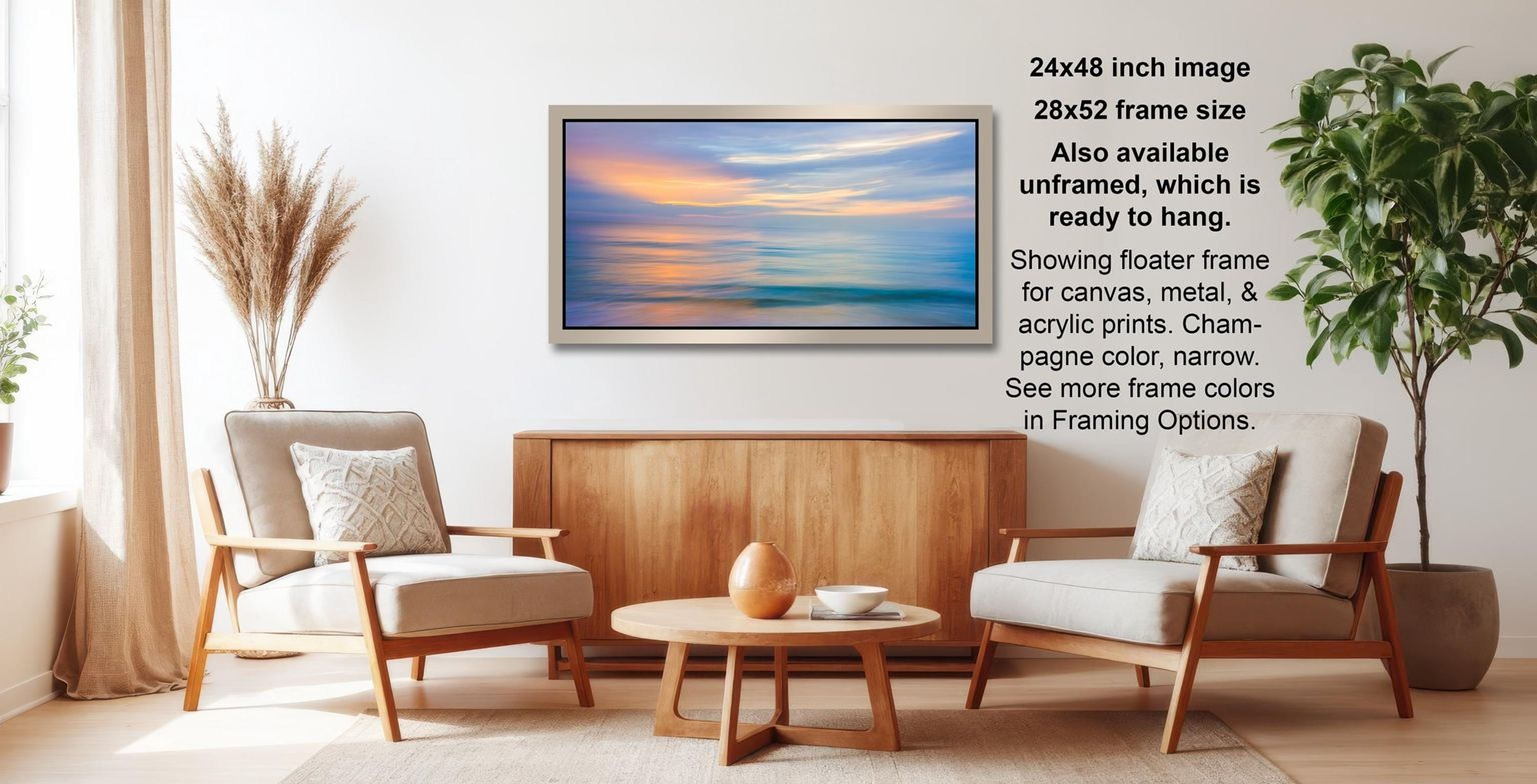 a living room with a wooden coffee table, two white armchairs, and a framed painting of a sunset over the ocean.