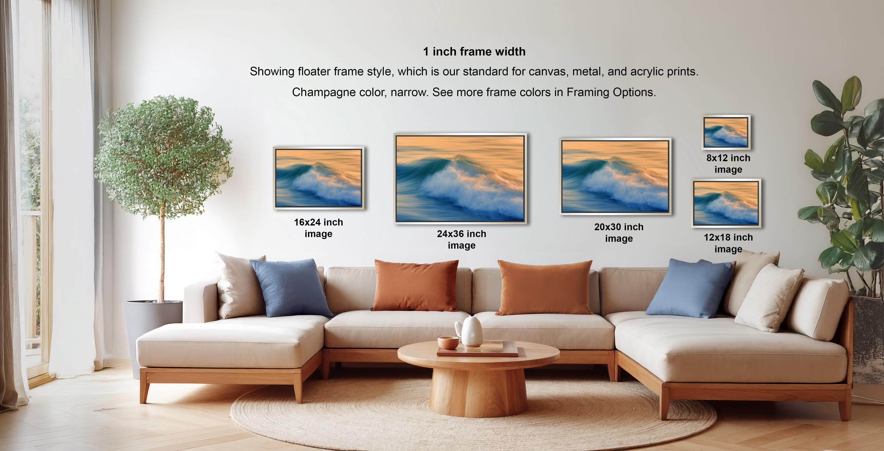a living room with a large sectional sofa, a coffee table, and a potted plant. There are four framed prints displayed on the wall, each with a different frame size ranging from 1 inch to 12 inches in width. The frames are arranged in a row, showcasing the different frame styles available for canvas, metal, and acrylic prints.