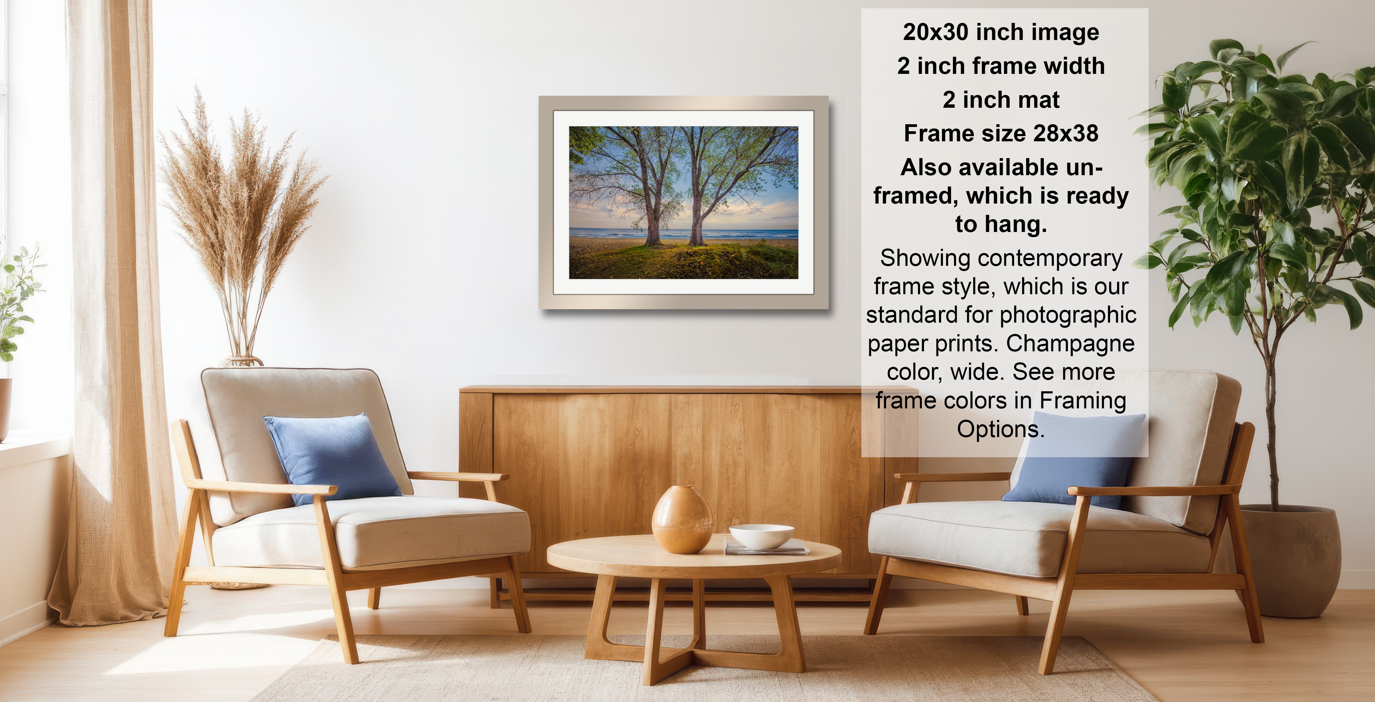 The image is a living room with two chairs, a coffee table, and a framed landscape photograph hanging on the wall. The photograph is framed in a modern style and is ready to hang.