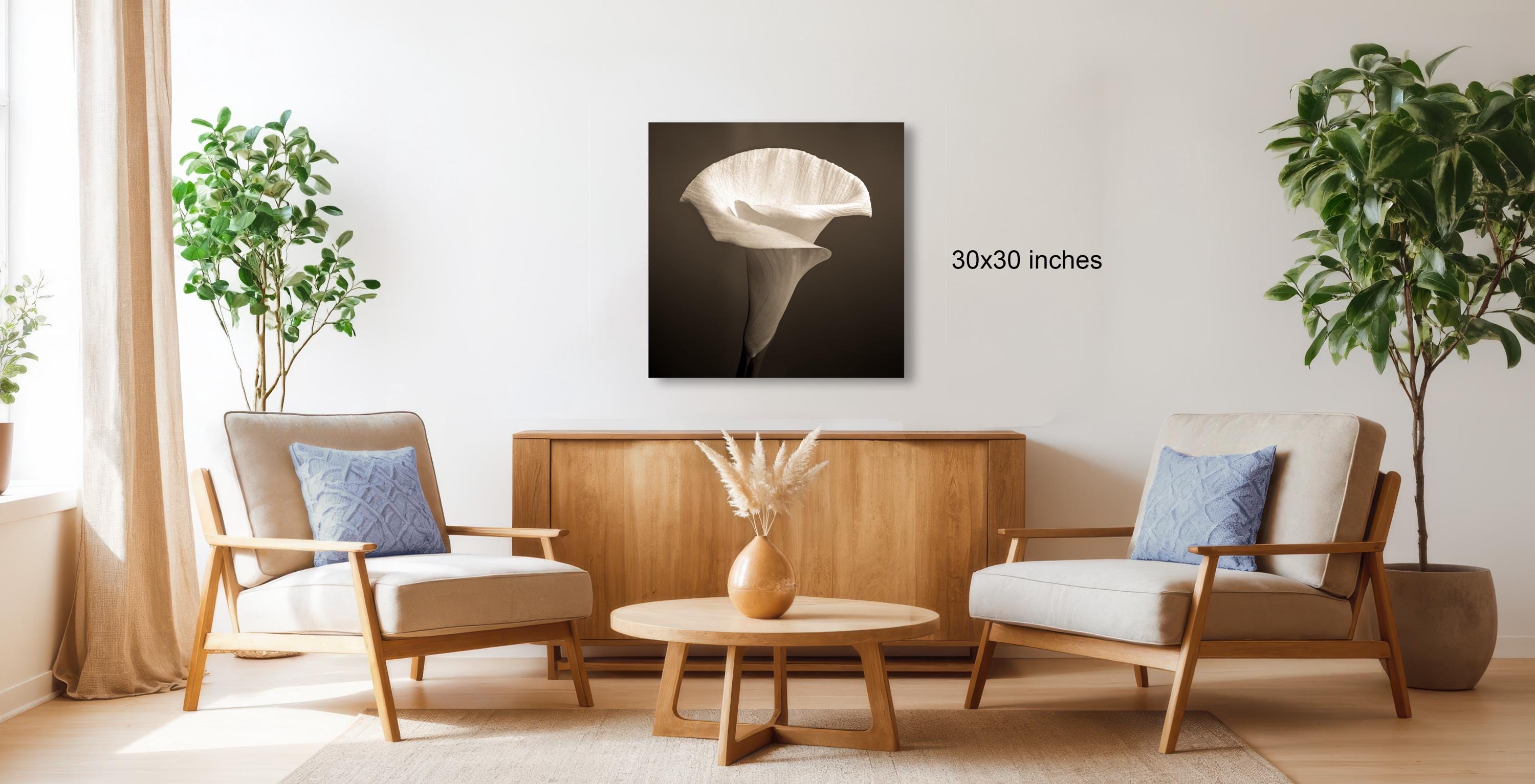 a living room with two armchairs, a coffee table, and a vase of flowers. The room is decorated with potted plants and a large white flower on the wall.