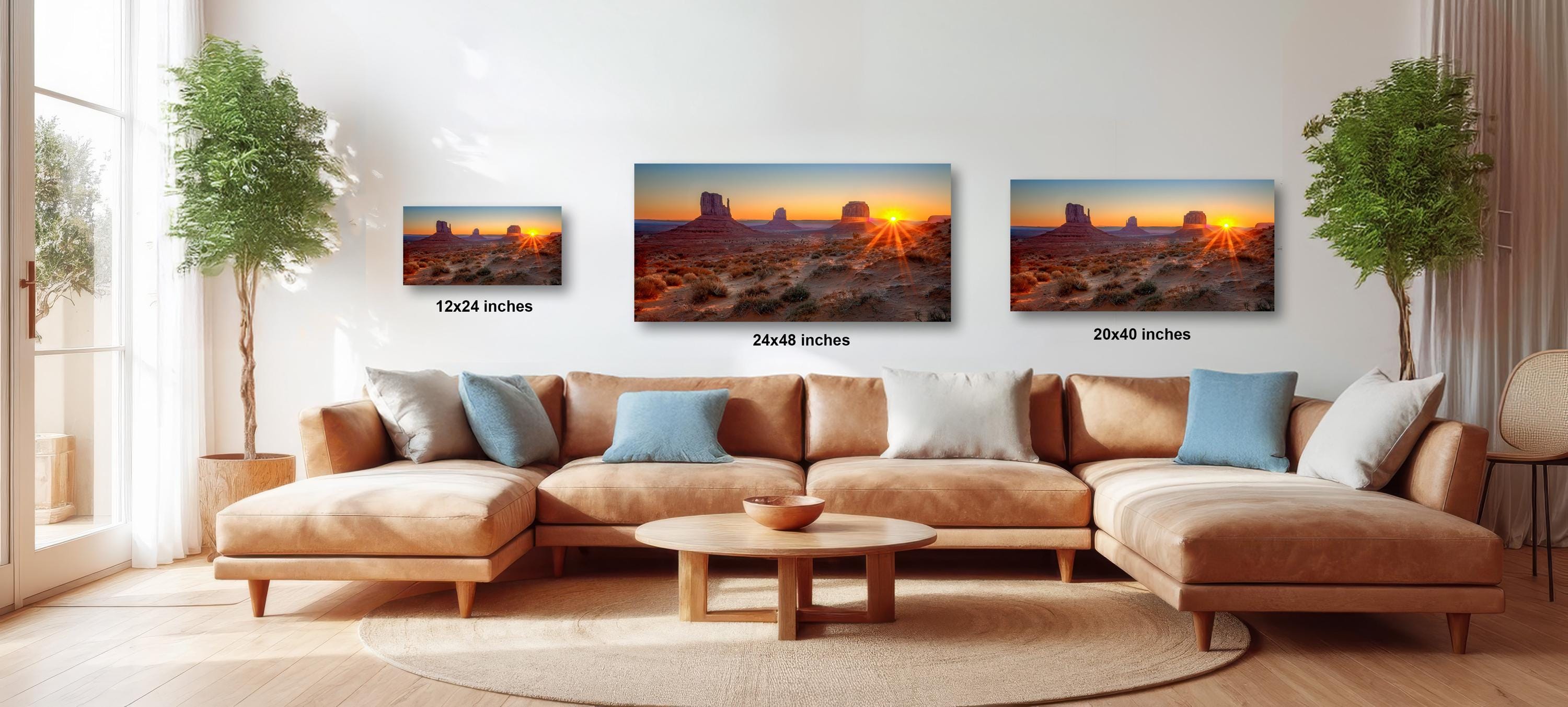 A living room with a large sectional sofa and a coffee table, along with three framed landscape photographs of a desert scene at sunset.
