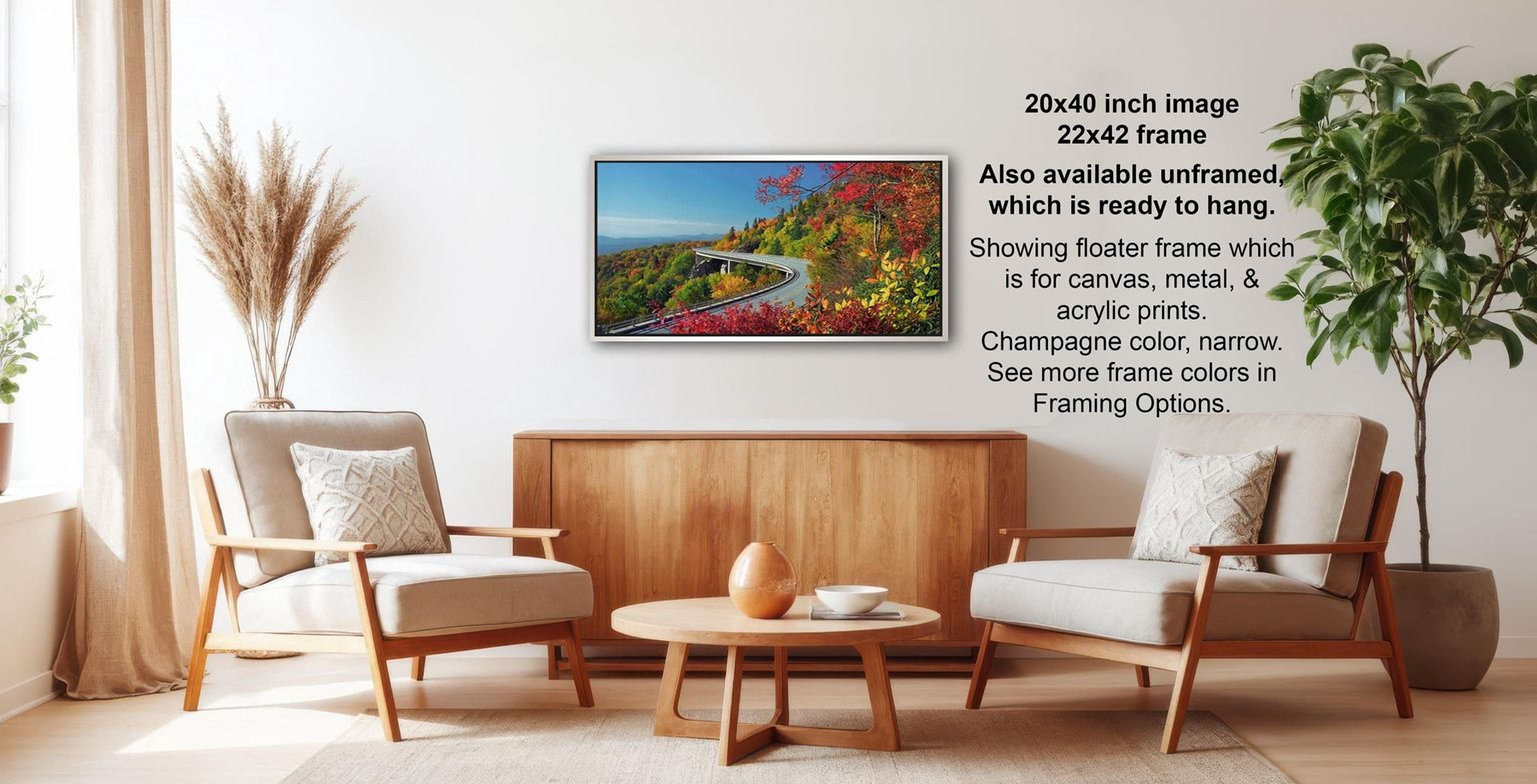 a living room with a wooden coffee table, two white armchairs, and a potted plant. A framed landscape photograph is hanging on the wall, and there is text providing information about the frame options.