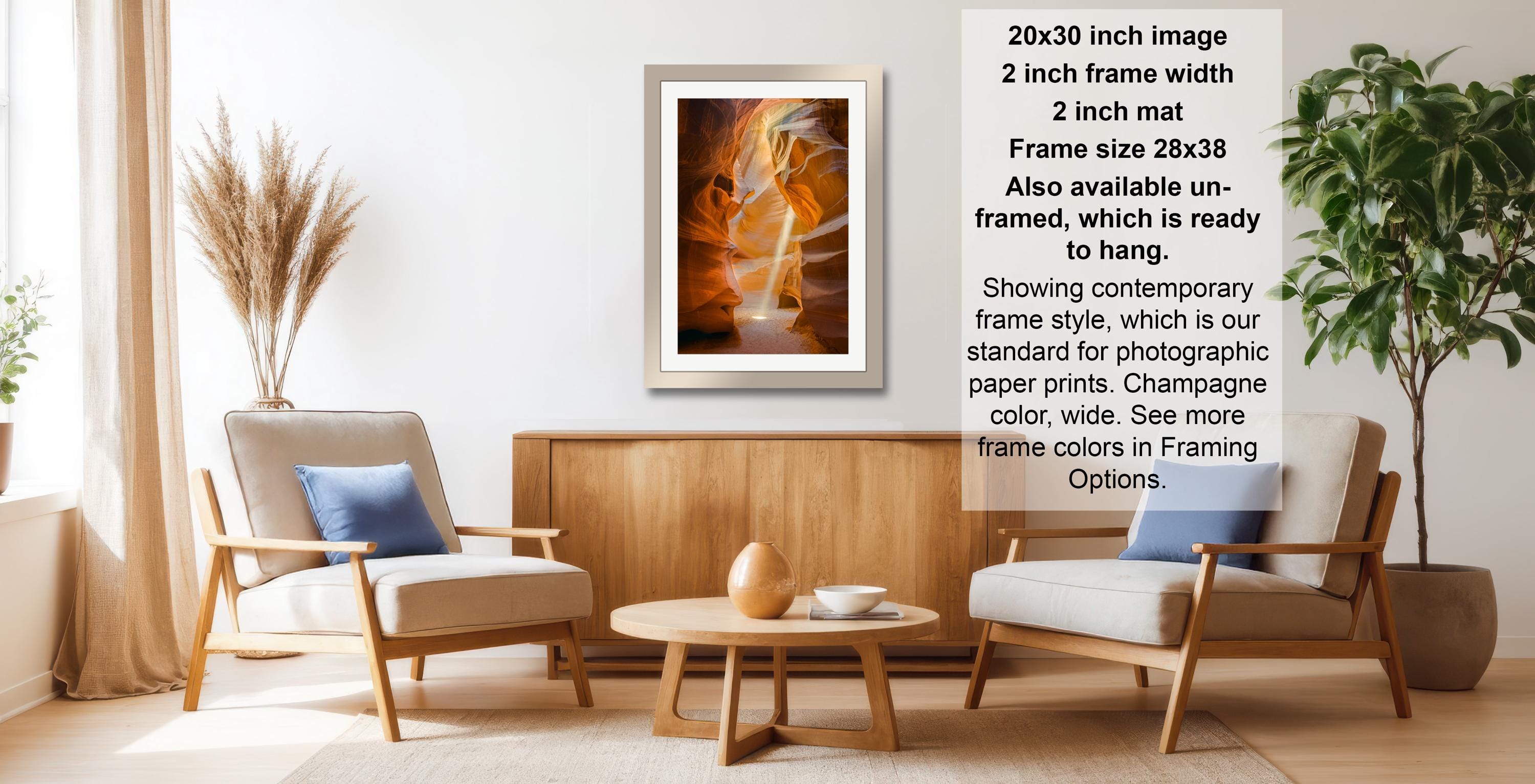 a modern living room with a wooden coffee table, two white armchairs, and a framed photograph hanging on the wall.