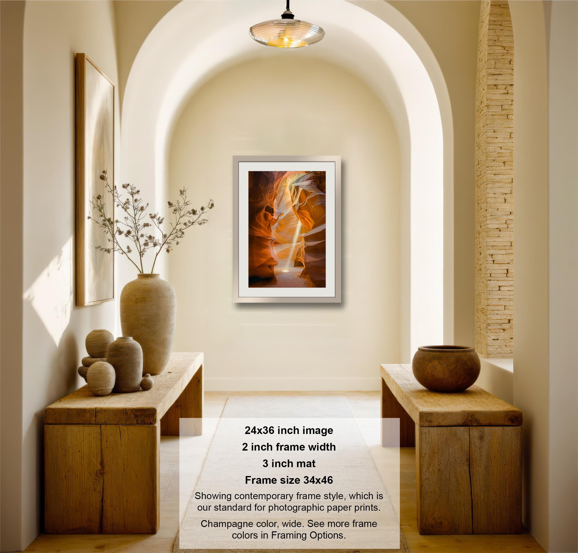 The image is a photograph of a hallway with a framed artwork hanging on the wall, wooden tables, and decorative items such as vases and a plant.
