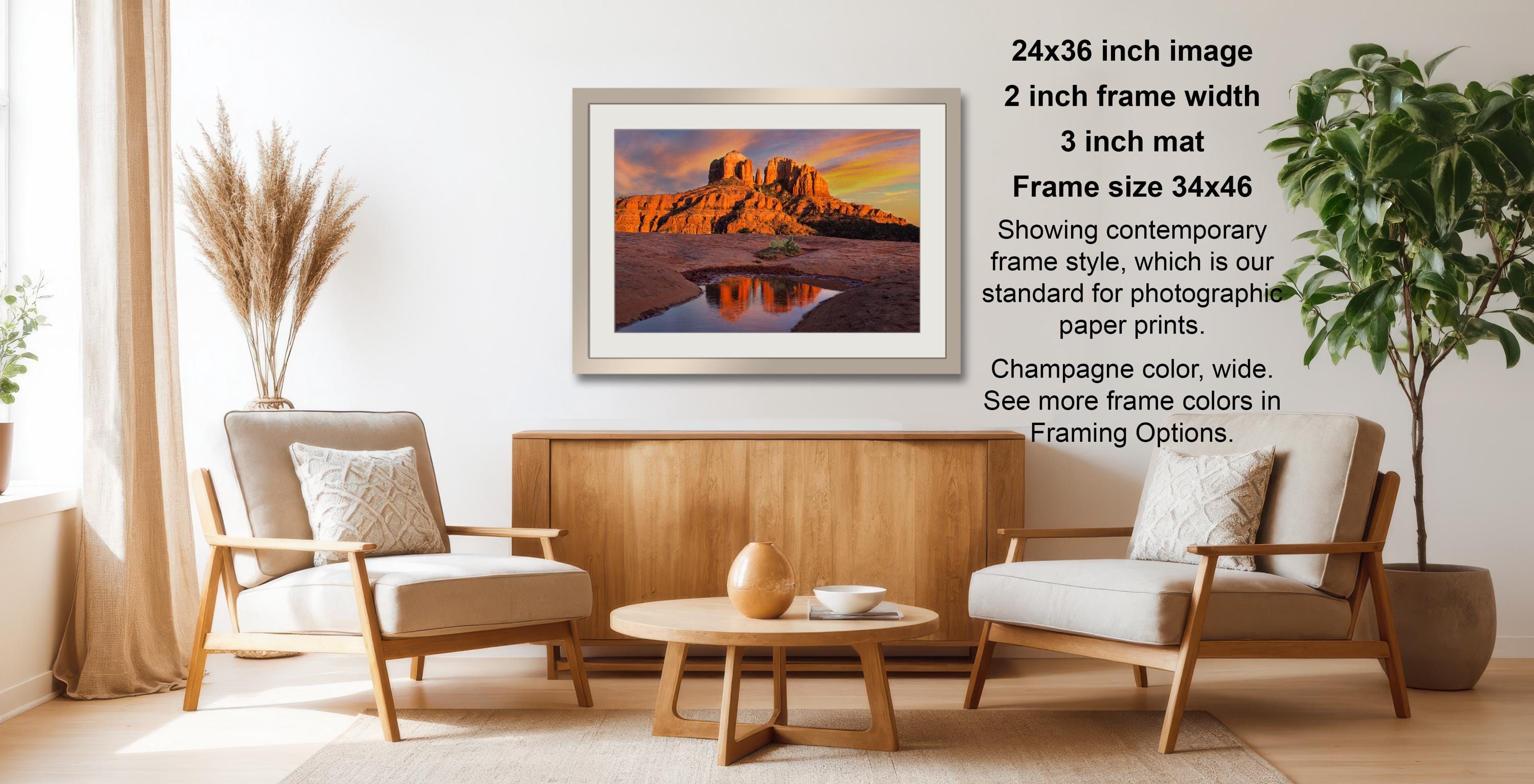 a serene living room with a wooden coffee table, two white armchairs, and a framed landscape photograph hanging on the wall.