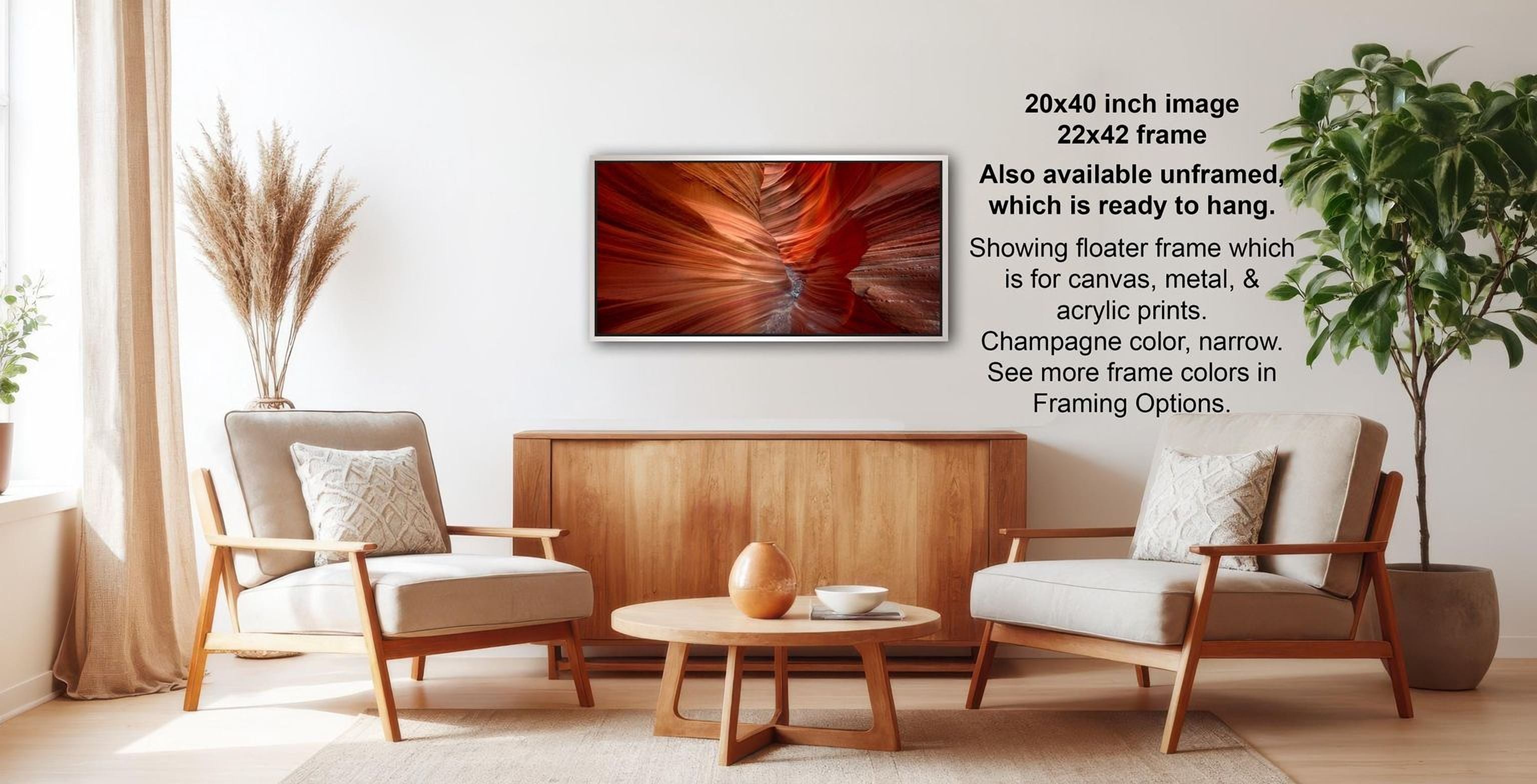 The image is a modern living room with a wooden coffee table, two white armchairs, and a wooden sideboard. Above the coffee table is a framed photograph of a red and orange abstract design.