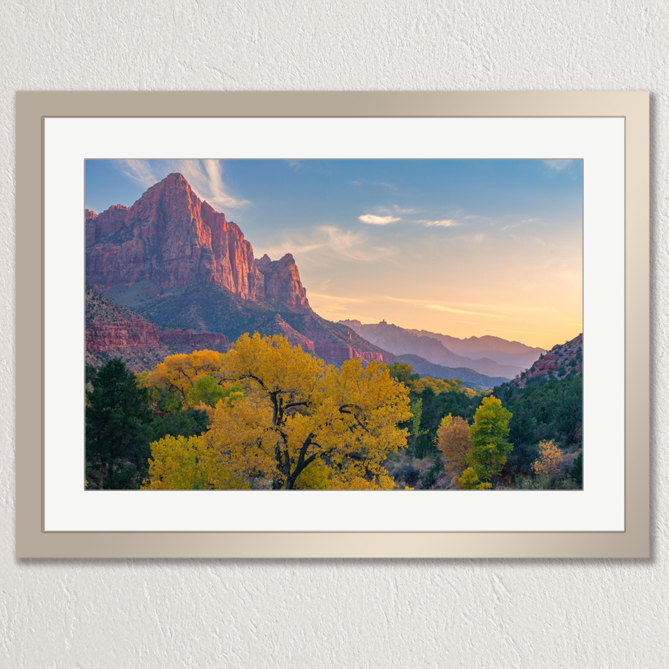 a breathtaking mountainous landscape with a vibrant display of fall foliage, including yellow and orange trees, set against a stunning backdrop of red rock formations and a clear blue sky.
