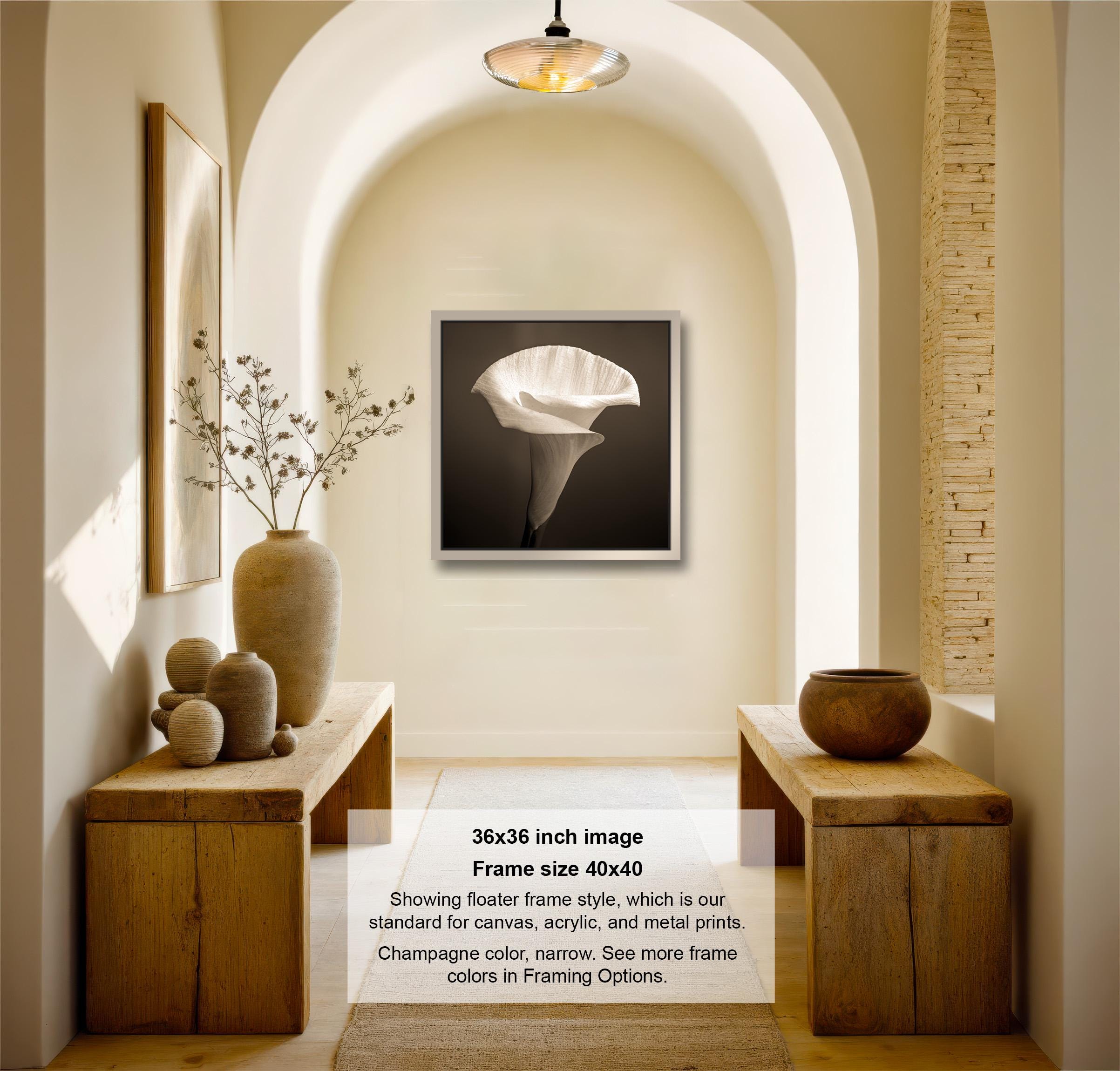 A modern and minimalist living room with a large framed photograph of a white flower on the wall, wooden tables, and decorative vases.