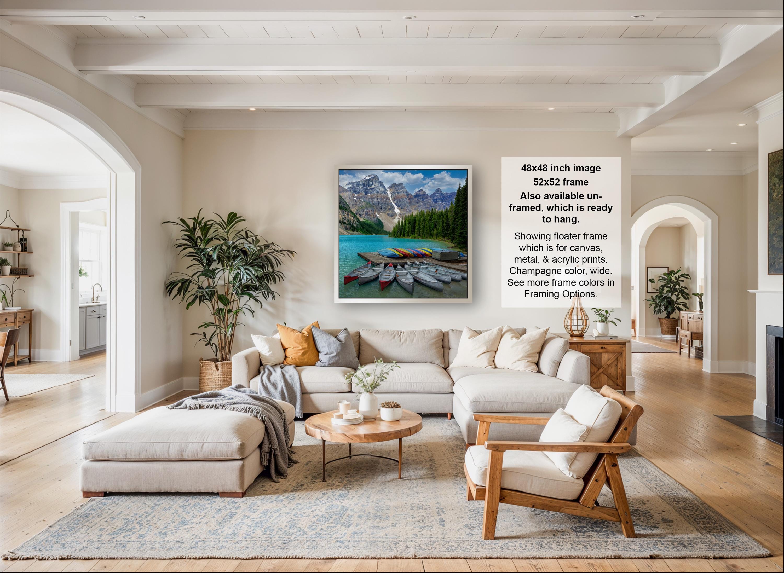 A large, high-quality framed image of a scenic mountain landscape is displayed on the wall of a spacious, well-lit living room.