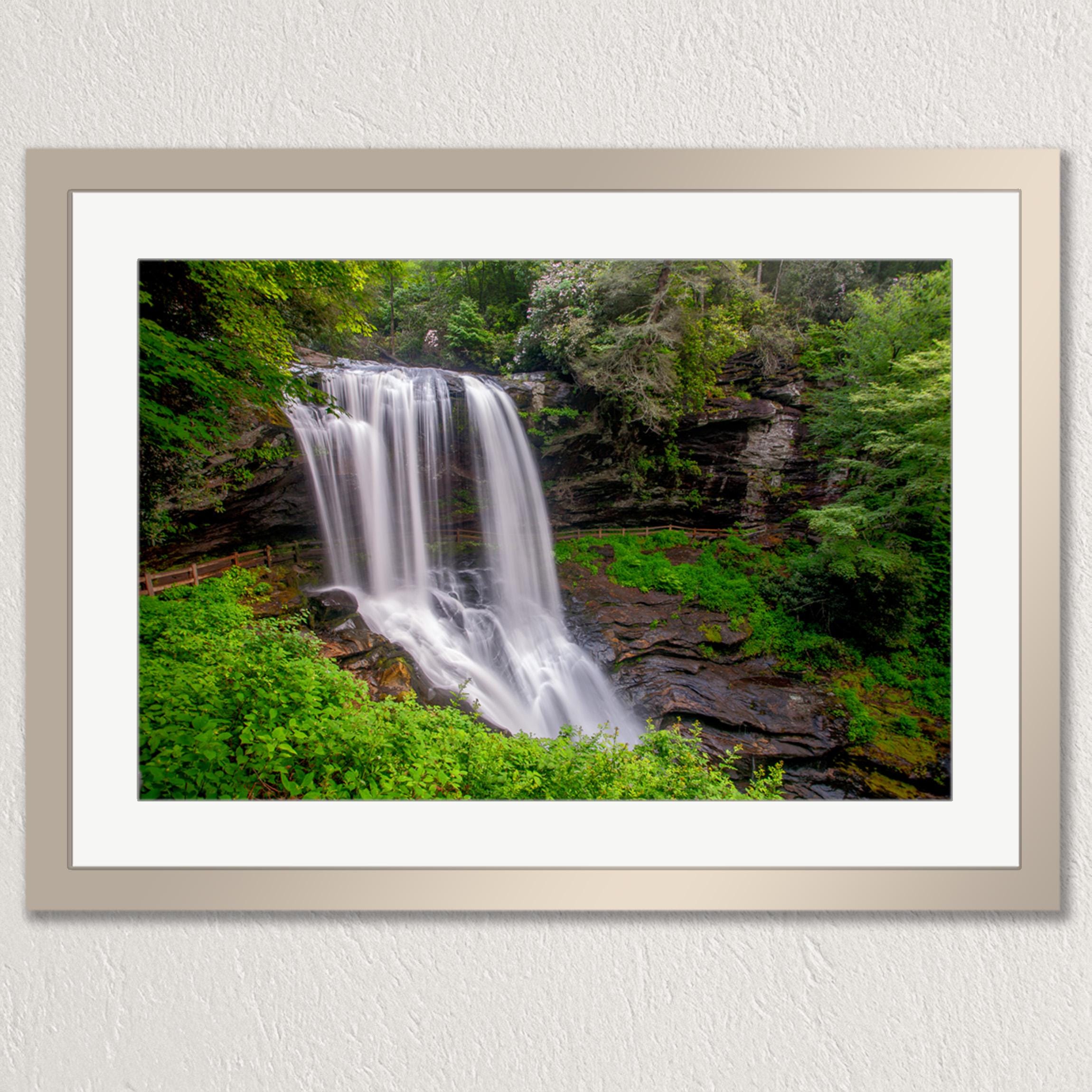 A framed photograph of a waterfall cascading down a rocky cliff surrounded by lush greenery.