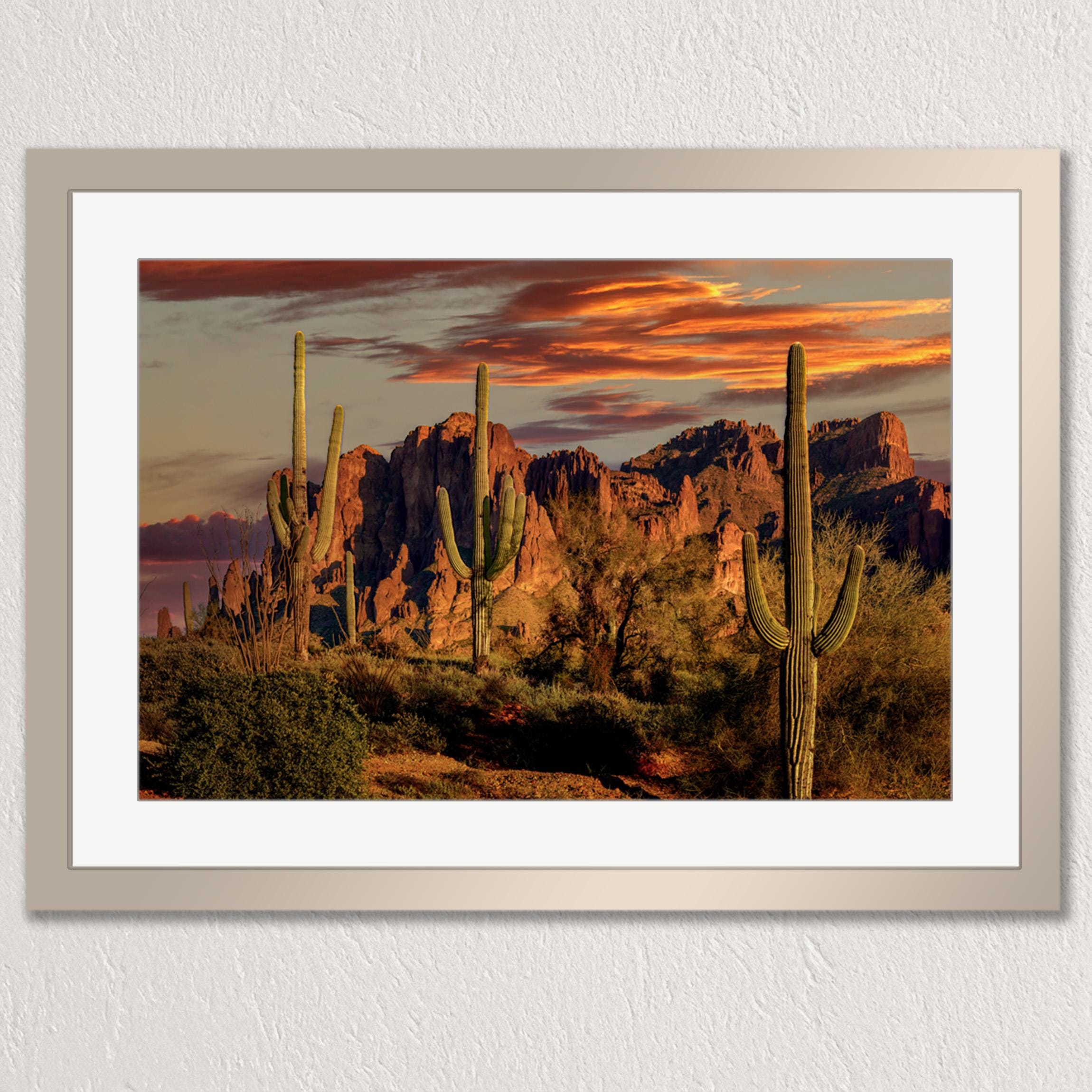 a desert landscape with towering red rock formations silhouetted against a vibrant sunset sky.