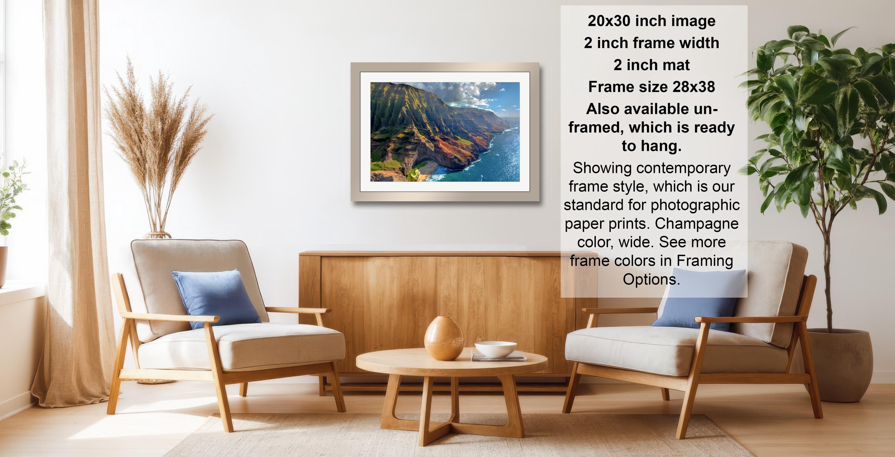 a living room with a wooden coffee table, two white armchairs, and a framed picture of a mountain landscape hanging on the wall.