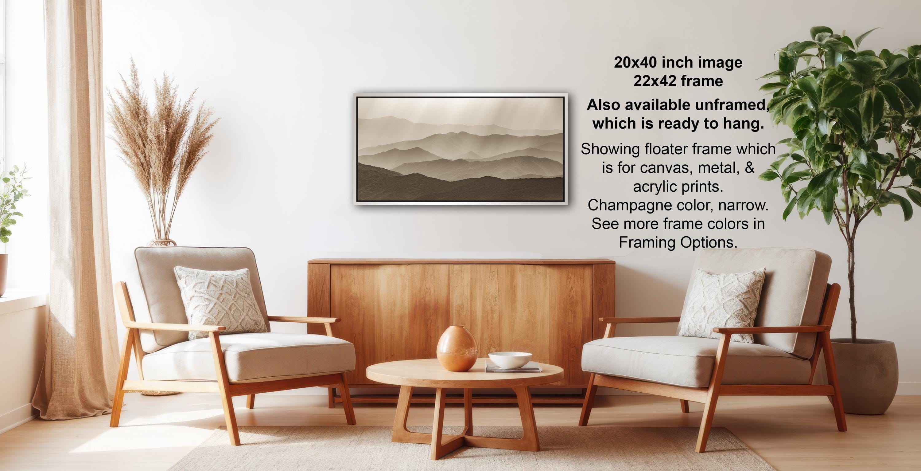 a living room with a wooden coffee table, two beige armchairs, and a framed landscape painting hanging on the wall.