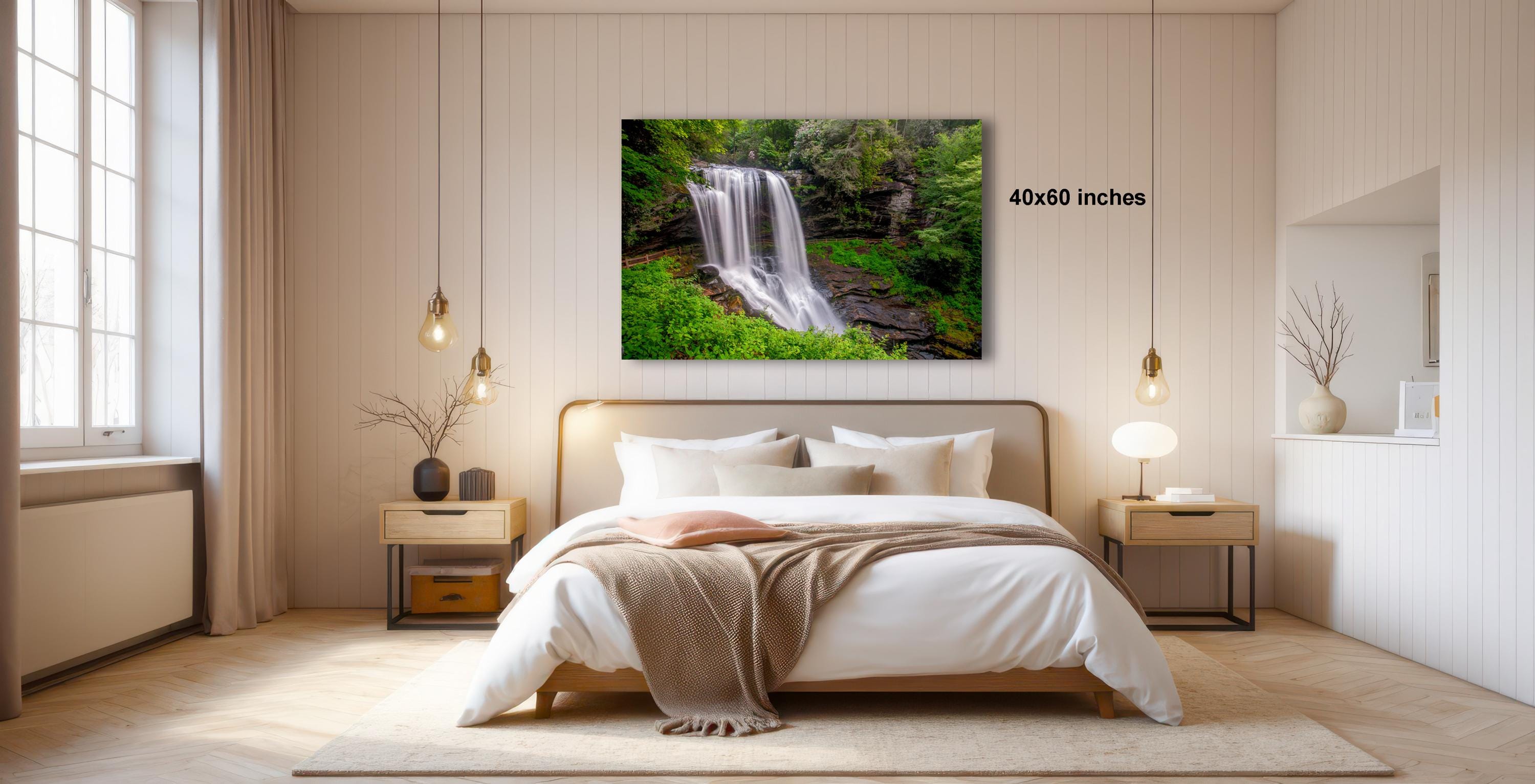 a serene bedroom with a large bed, wooden furniture, and a framed photograph of a waterfall hanging on the wall.