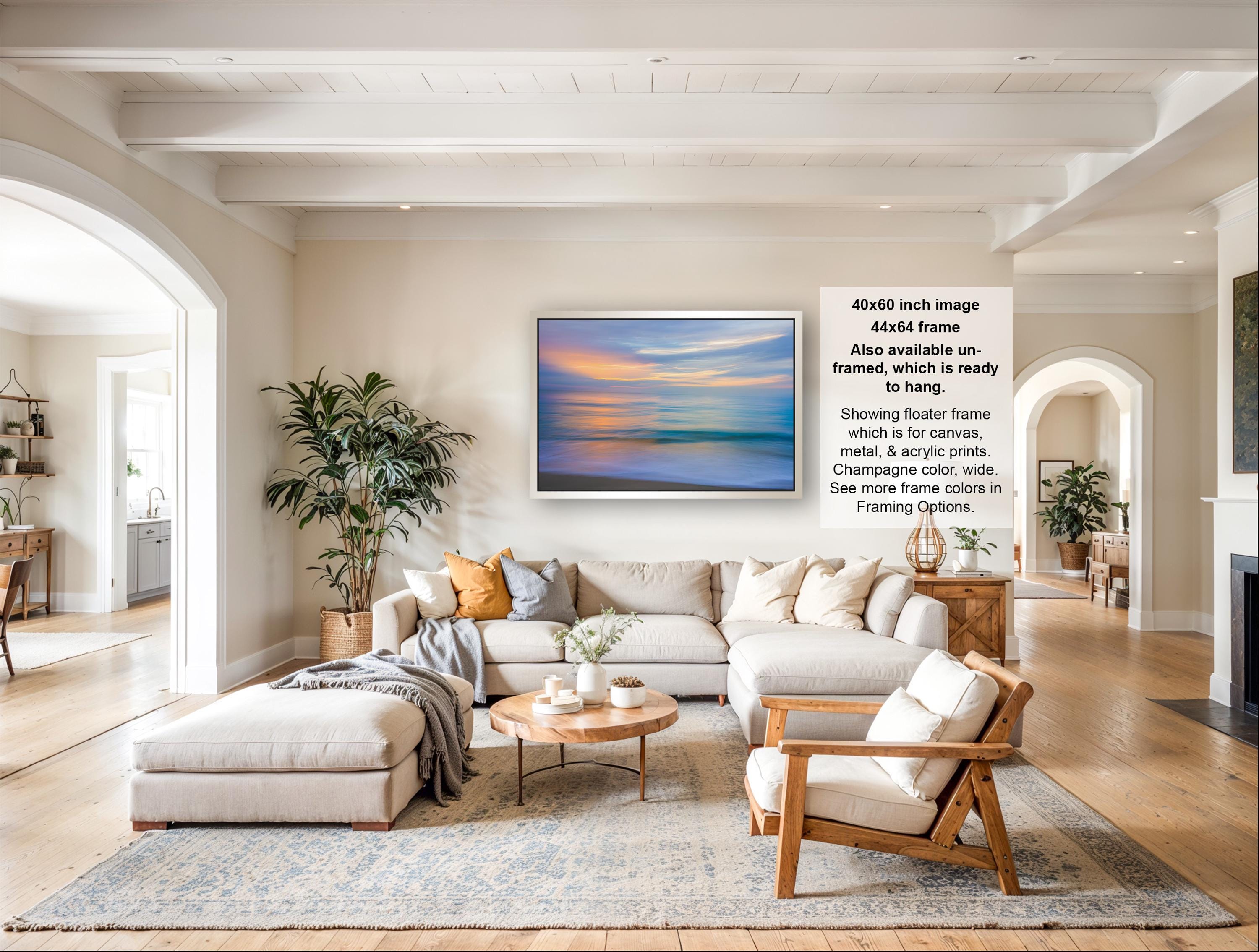 The image is a spacious living room with a large sectional sofa, a coffee table, and a fireplace. The room is decorated with various plants and has a neutral color palette.