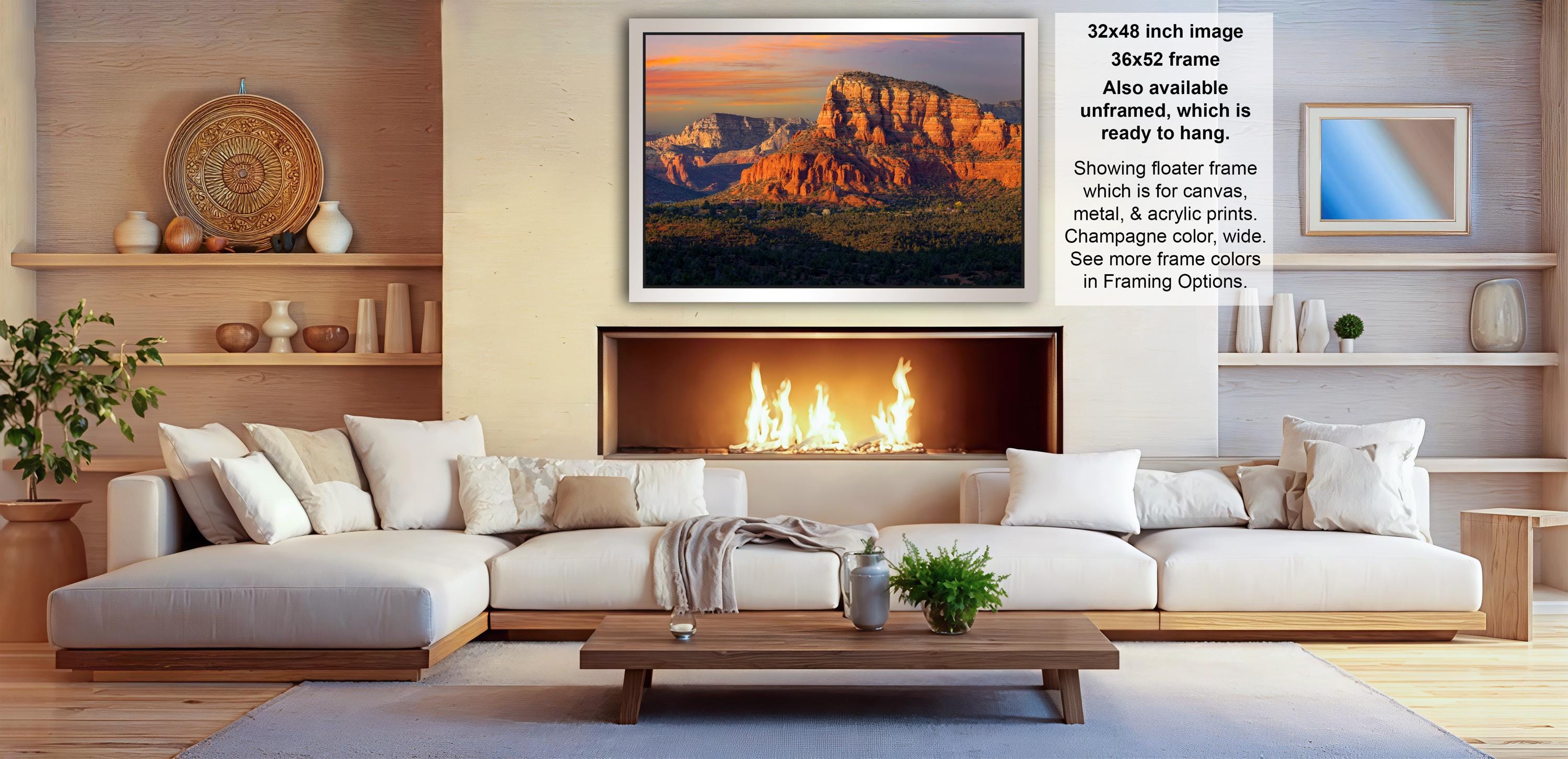 a cozy living room with a large white sectional sofa, a fireplace, and a framed picture of a scenic mountain landscape.