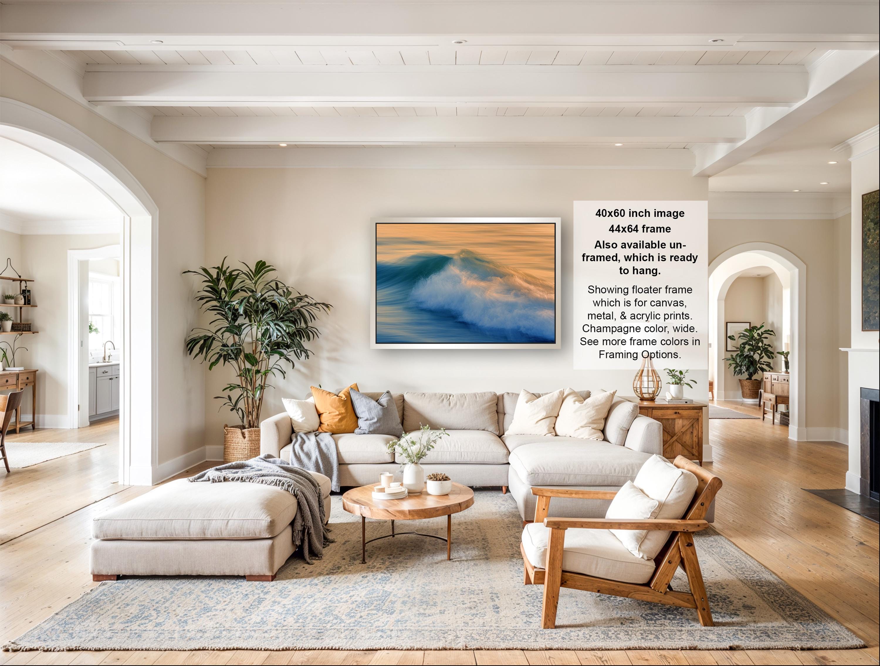 The image is a spacious living room with a large sectional sofa, a coffee table, and a fireplace. The room is decorated with various plants and has a neutral color palette.