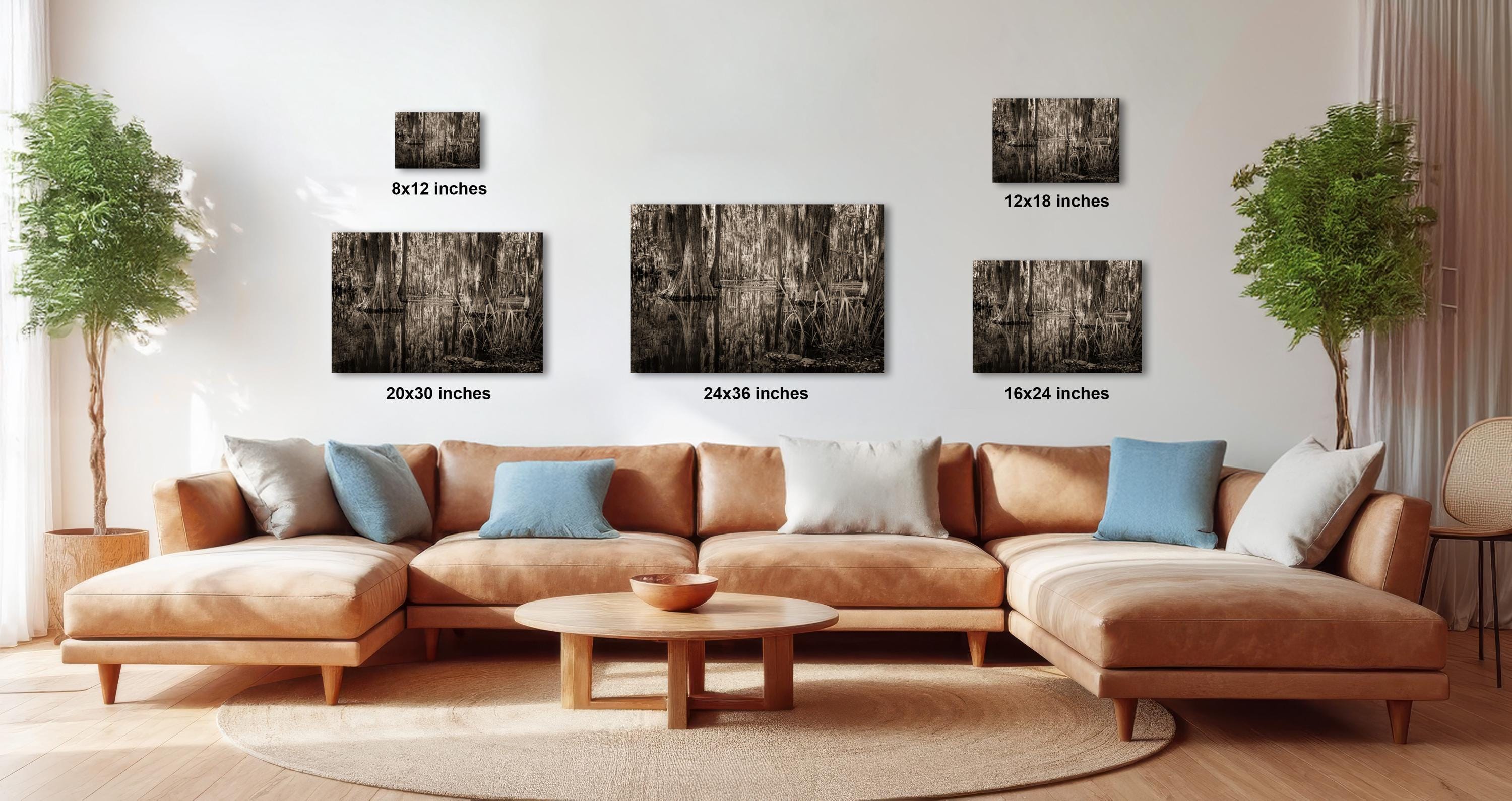 a modern living room with a large sectional sofa, a coffee table, and several potted plants. The sofa is positioned in front of a wall with three framed artworks displayed above it, each with a different size and resolution.