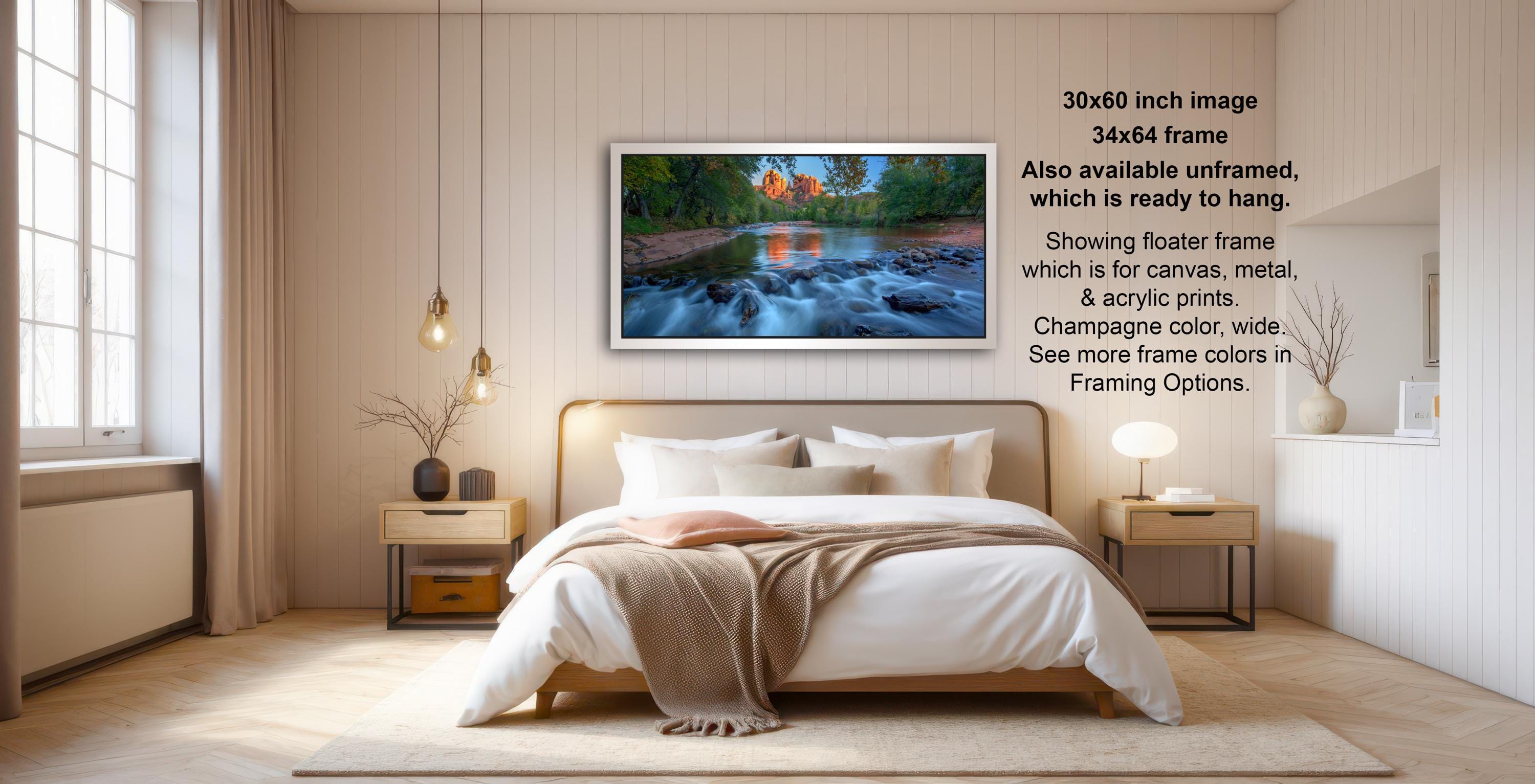The image is a modern bedroom with a large bed, wooden furniture, and a framed landscape photograph hanging on the wall.