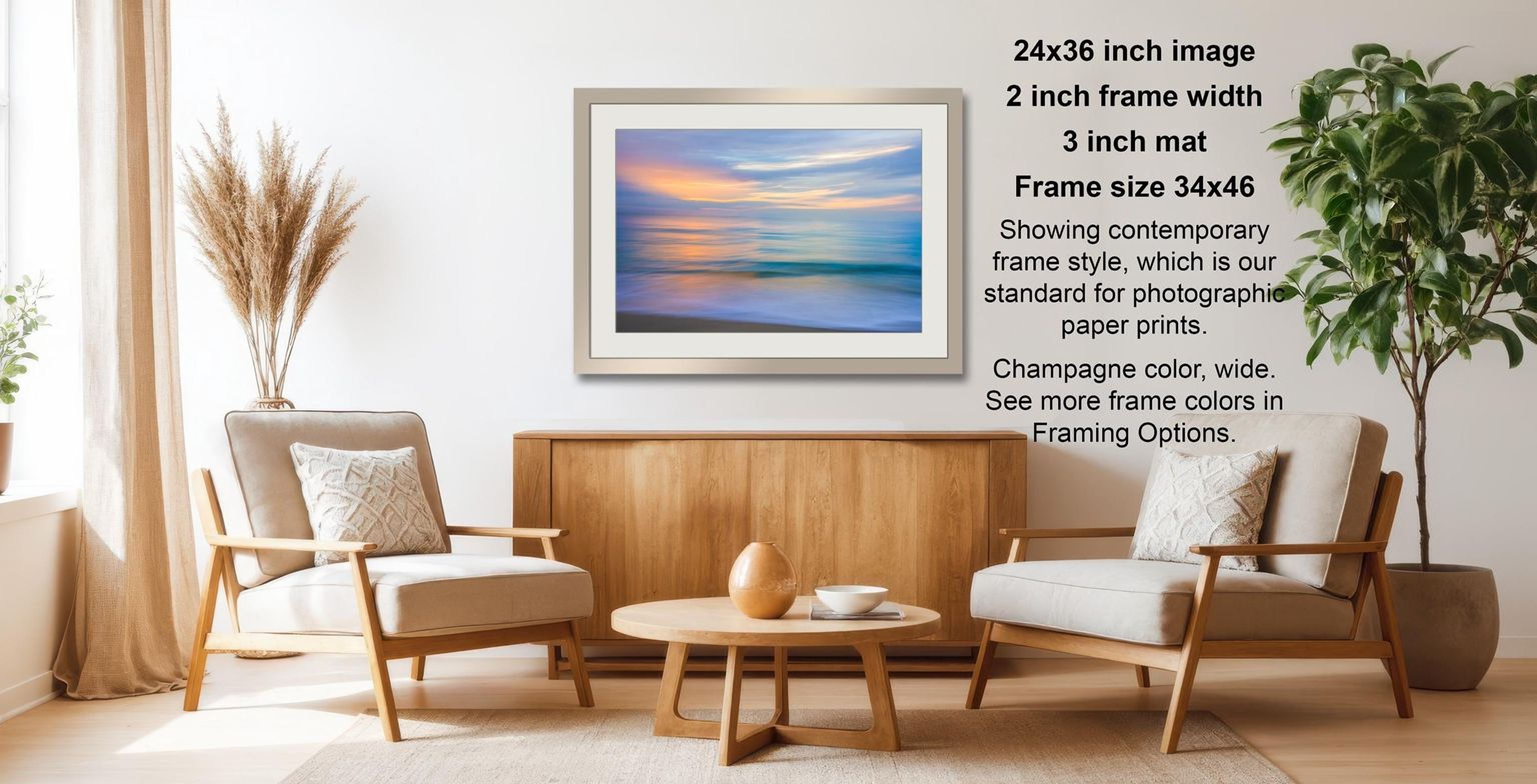 a living room with a framed landscape painting hanging on the wall, two white armchairs, a wooden coffee table, and a potted plant.