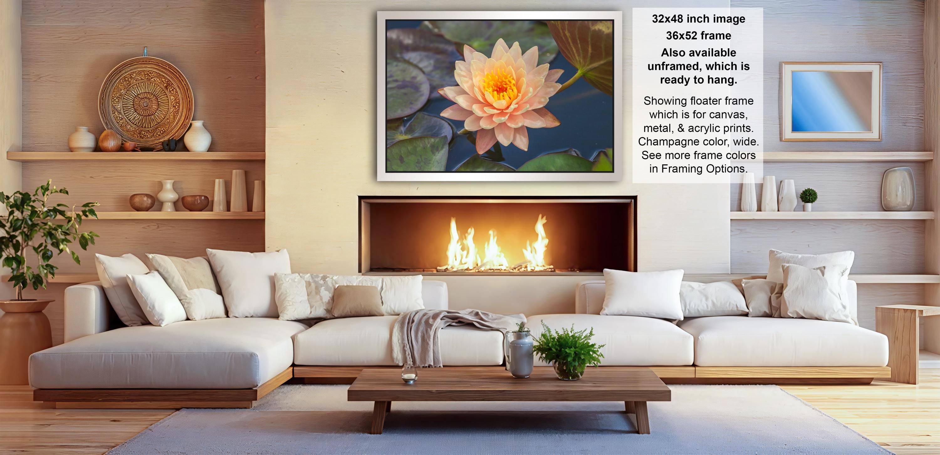 a cozy living room with a fireplace, white sofas, and a coffee table. The room has a warm and inviting atmosphere, with a large framed photograph of a water lily on the wall and a fireplace with a fire burning.