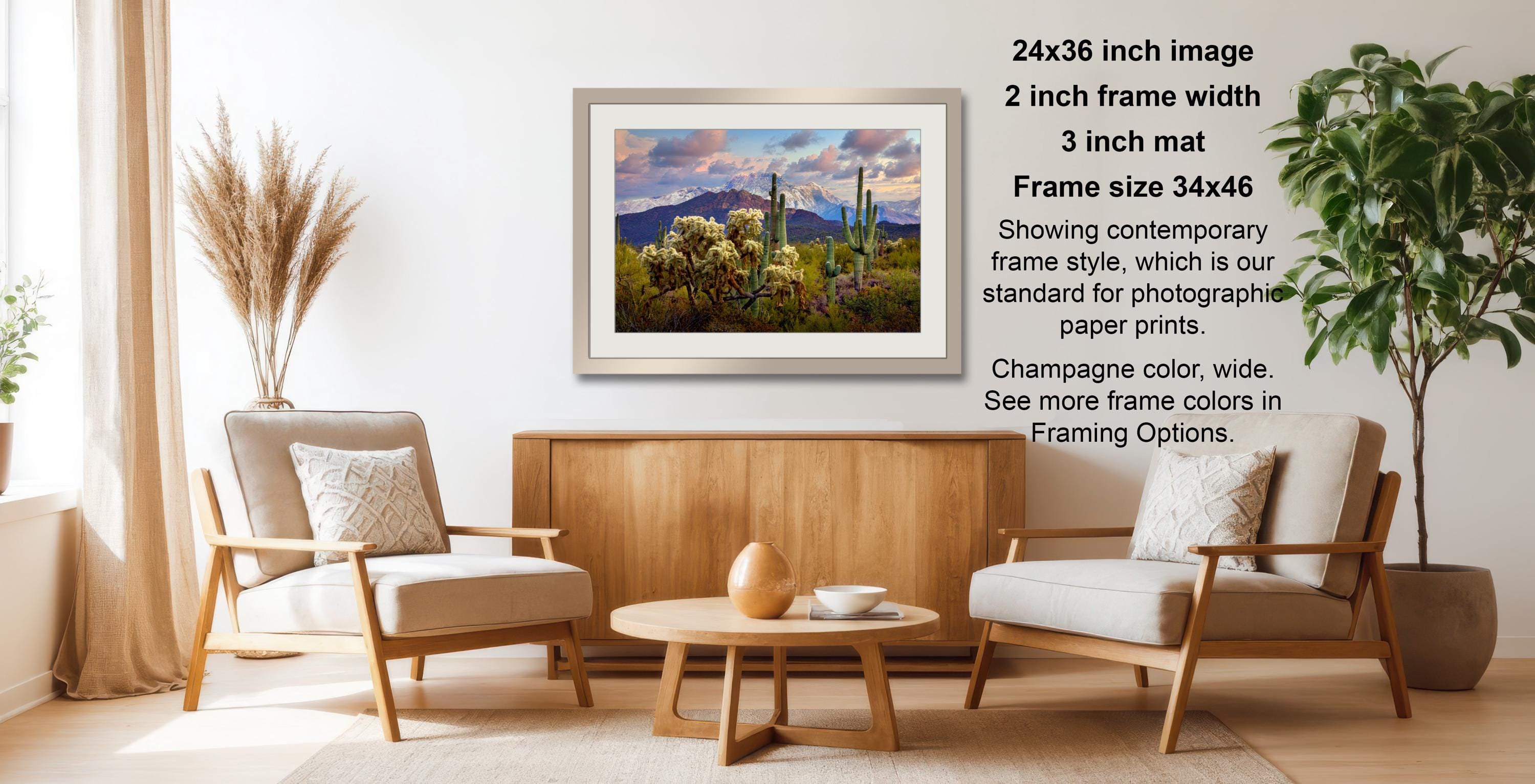 a cozy living room with a wooden coffee table, two beige armchairs, and a framed landscape photograph hanging on the wall.