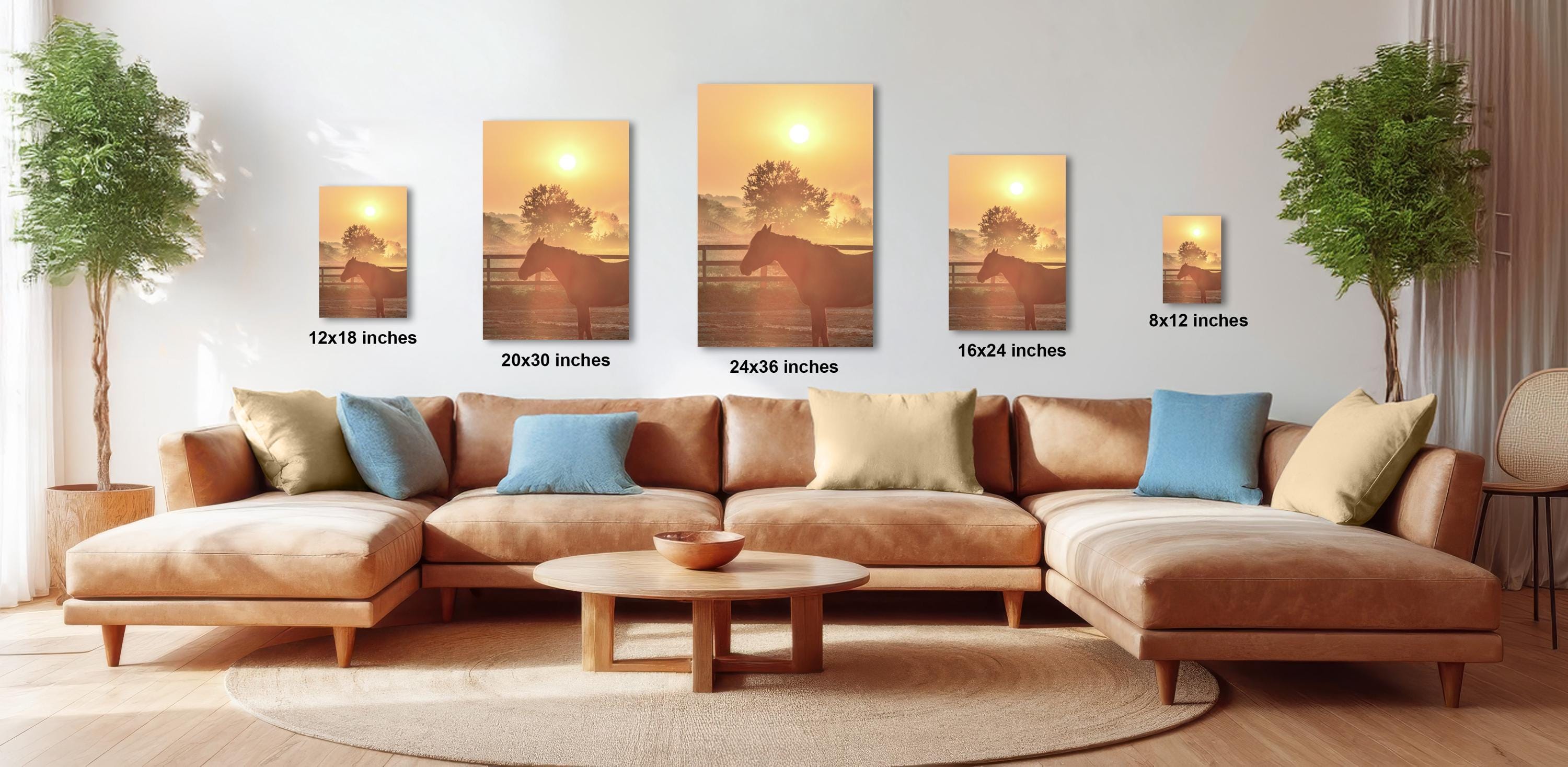 The image is a modern living room with a large sectional sofa, a coffee table, and several potted plants. The sofa is positioned in front of a wall with four framed pictures of horses, each varying in size and orientation. The room has a warm and inviting atmosphere, with the natural light coming in from the windows.