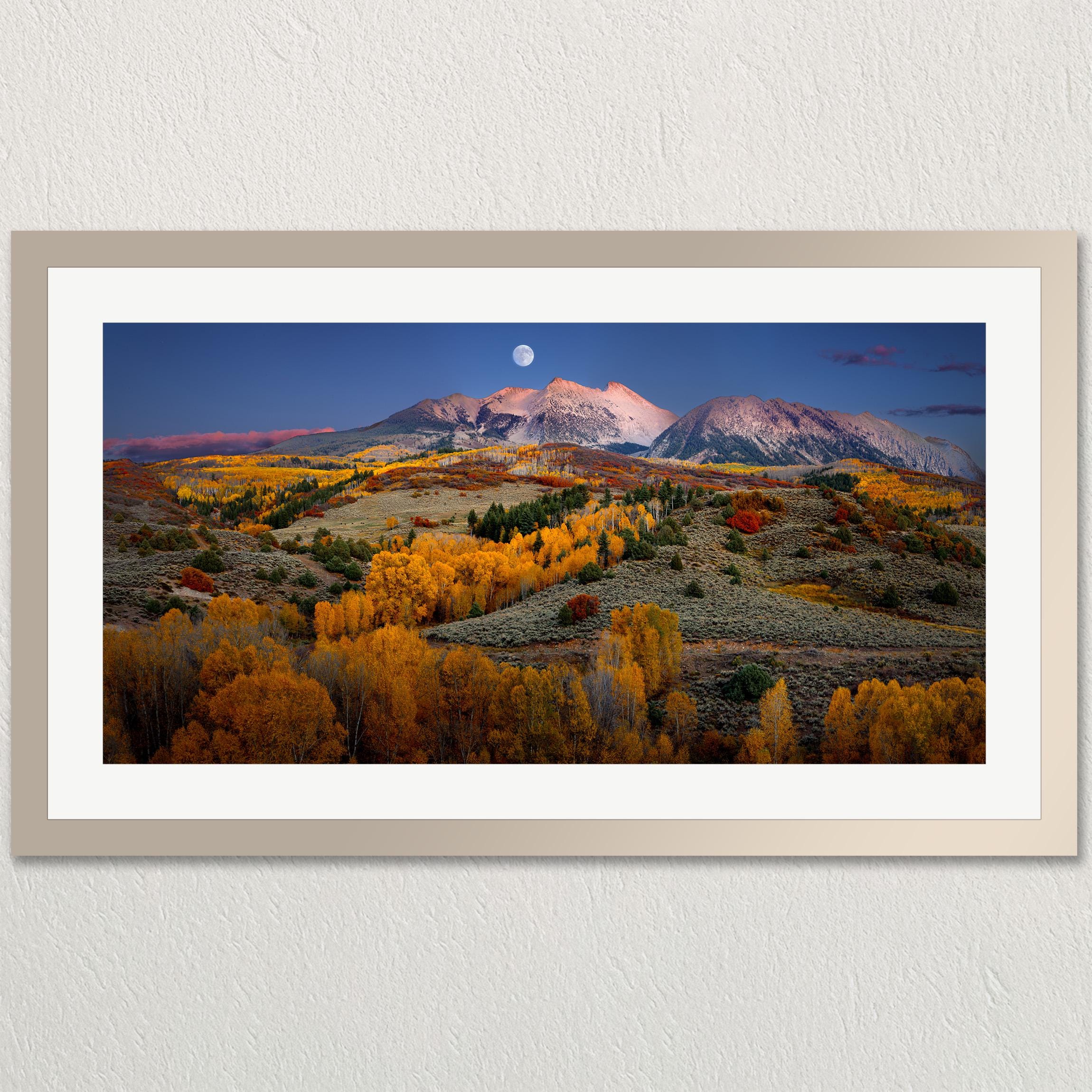 The image is a framed landscape photograph depicting a mountainous, autumnal valley with a full moon in the sky.