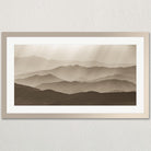 A framed photograph depicting a serene landscape of rolling hills and mountains, with a hazy, atmospheric quality to the scene.