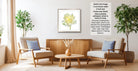 a cozy living room with two beige armchairs, a wooden coffee table, and a framed picture of a yellow flower on the wall.