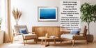 a living room with a framed picture of a blue sky and mountains hanging on the wall. The room has two white chairs, a wooden coffee table, and a potted plant. The image also includes text providing information about the frame size and color options.