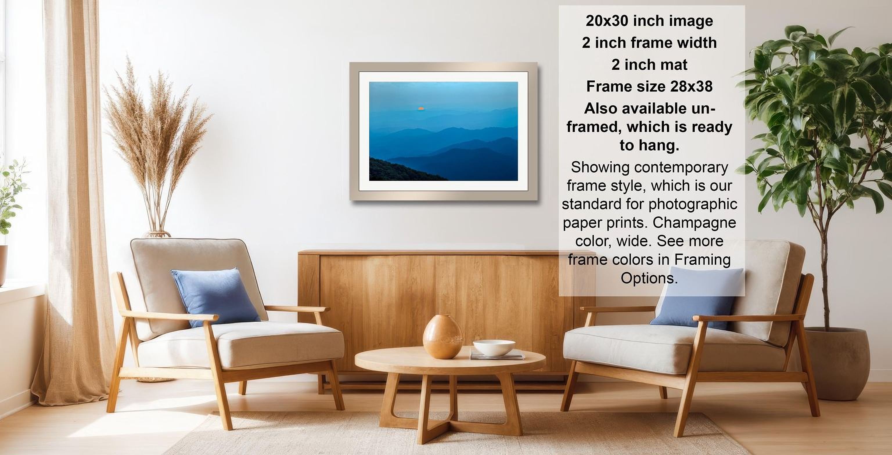 a living room with a framed picture of a blue sky and mountains hanging on the wall. The room has two white chairs, a wooden coffee table, and a potted plant. The image also includes text providing information about the frame size and color options.