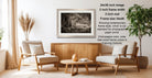 a cozy living room with a wooden coffee table, two beige armchairs, and a framed black and white photograph of a forest scene hanging on the wall.