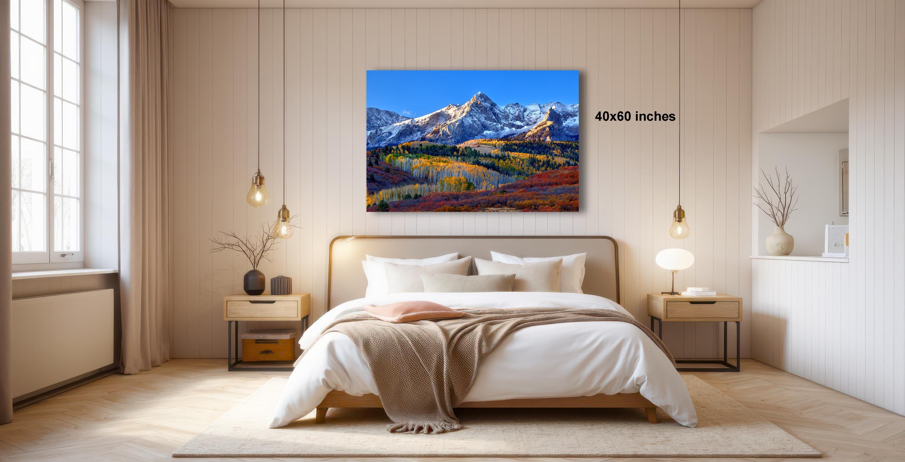 a bedroom with a large bed, a nightstand, and a painting of a mountain landscape hanging on the wall.