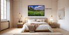 a serene bedroom with a large bed, wooden furniture, and a painting of a lush green field with trees hanging above it.