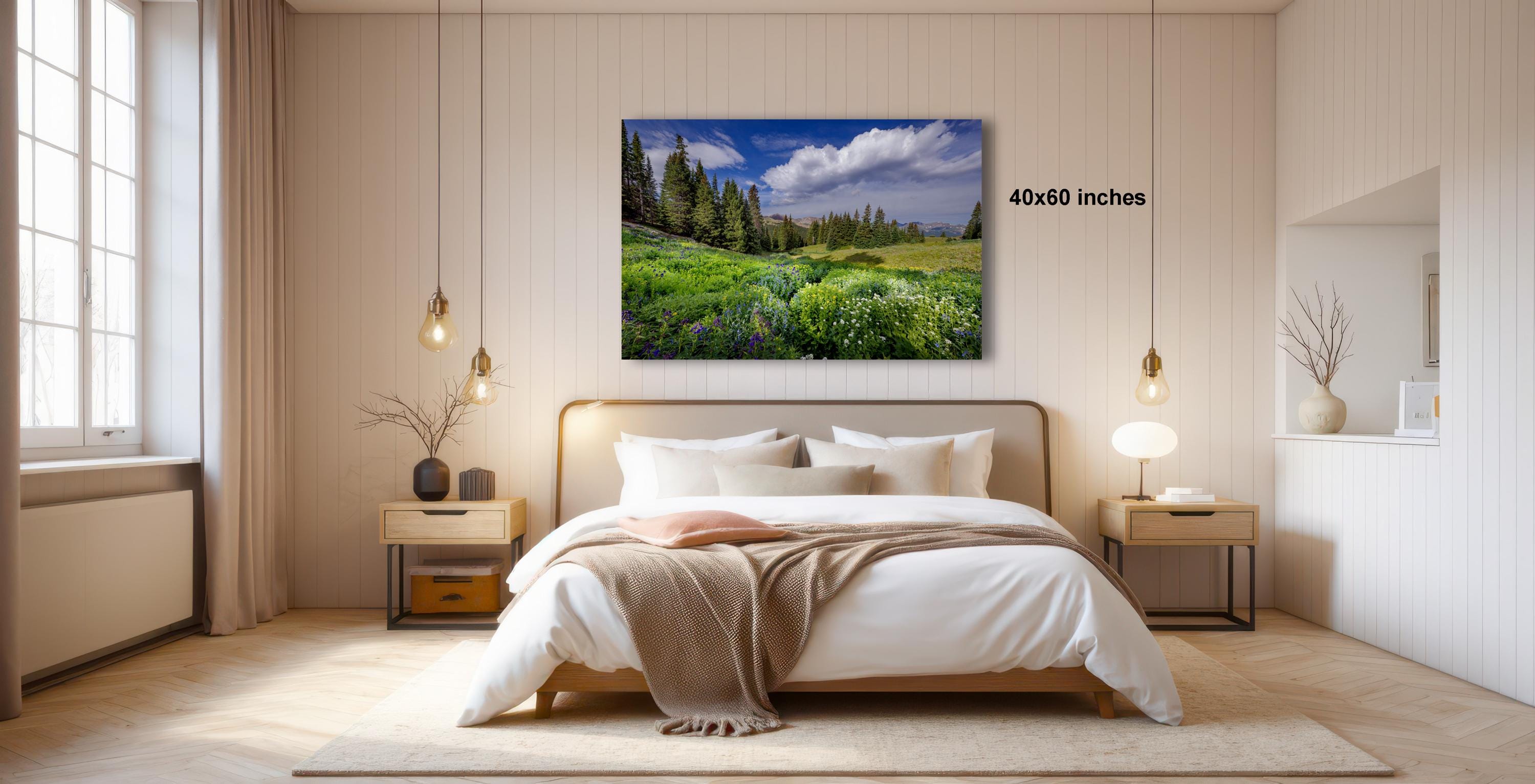 a serene bedroom with a large bed, wooden furniture, and a painting of a lush green field with trees hanging above it.
