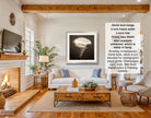 The image is a living room with a fireplace, a white sofa, a wooden coffee table, and a framed photograph of a white flower hanging on the wall.