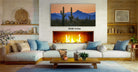 a cozy living room with a fireplace, a large painting of a desert landscape, and a comfortable couch and coffee table.
