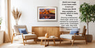 a living room with a framed landscape photograph hanging on the wall, a wooden coffee table in the center, and two chairs facing each other.