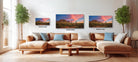 a living room with a large sectional sofa, a coffee table, and three framed landscape paintings hanging on the wall above the sofa.